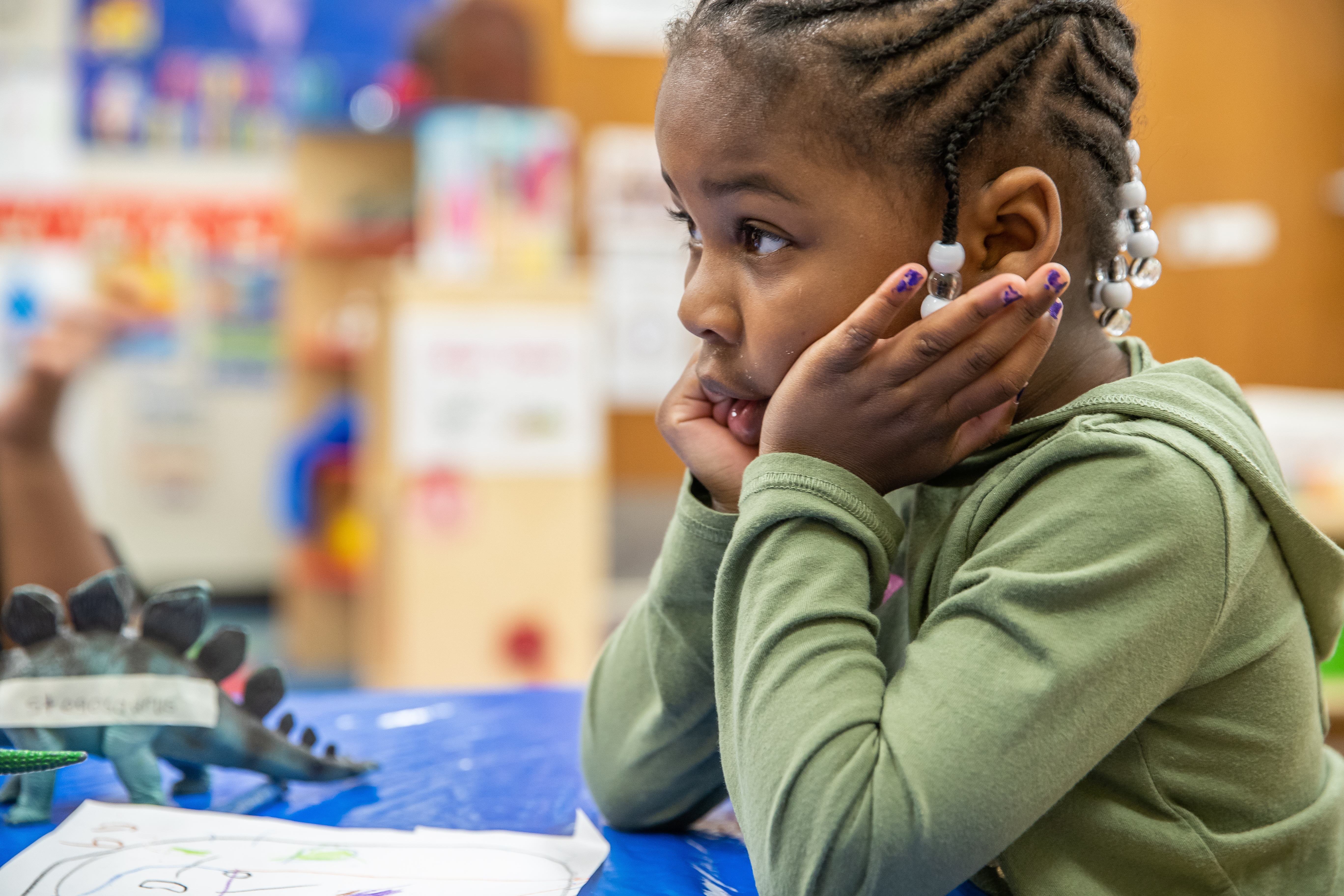 Prius Winters, 4, a pre-kindergarten student at Avondale Meadows YMCA Early Learning Center in Indianapolis, waits for teacher, Cecelia Washington, to label her drawing of her favorite dinosaur during a lesson on Tuesday, April 30, 2019.
