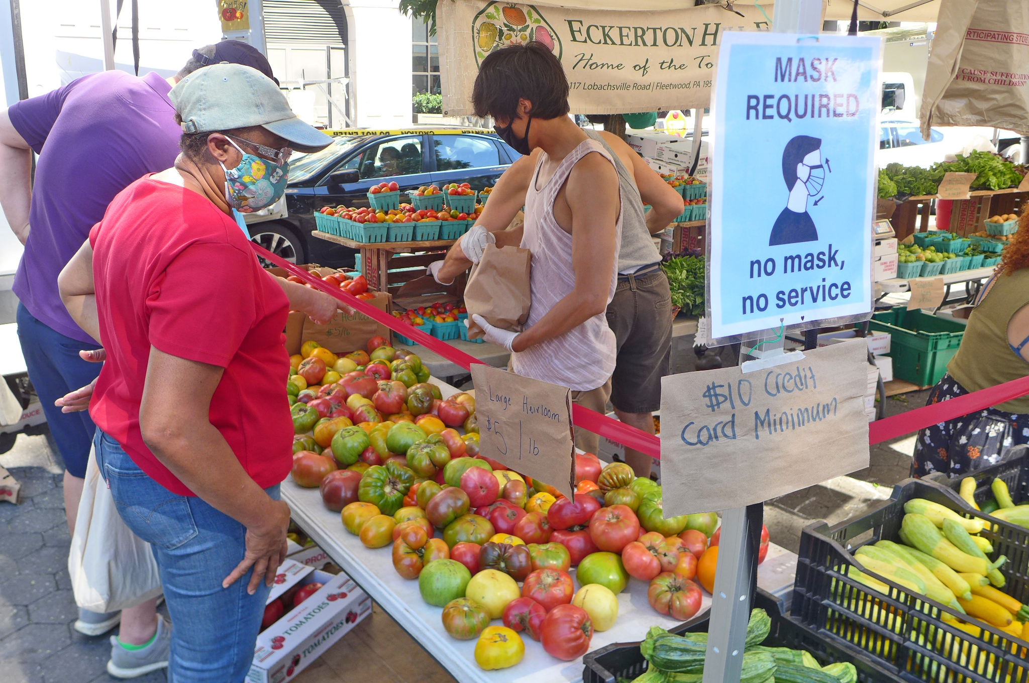 A woman in a baseball cap looks over the many varieties of heirloom tomatoes.