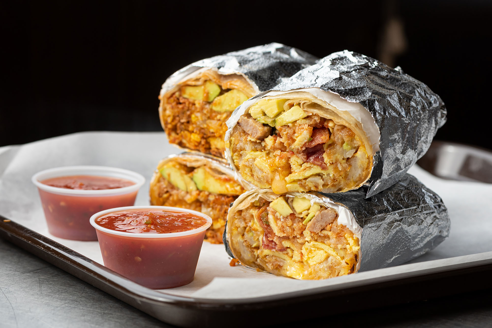 Breakfast burritos filled with bacon and sausage stacked atop one another.