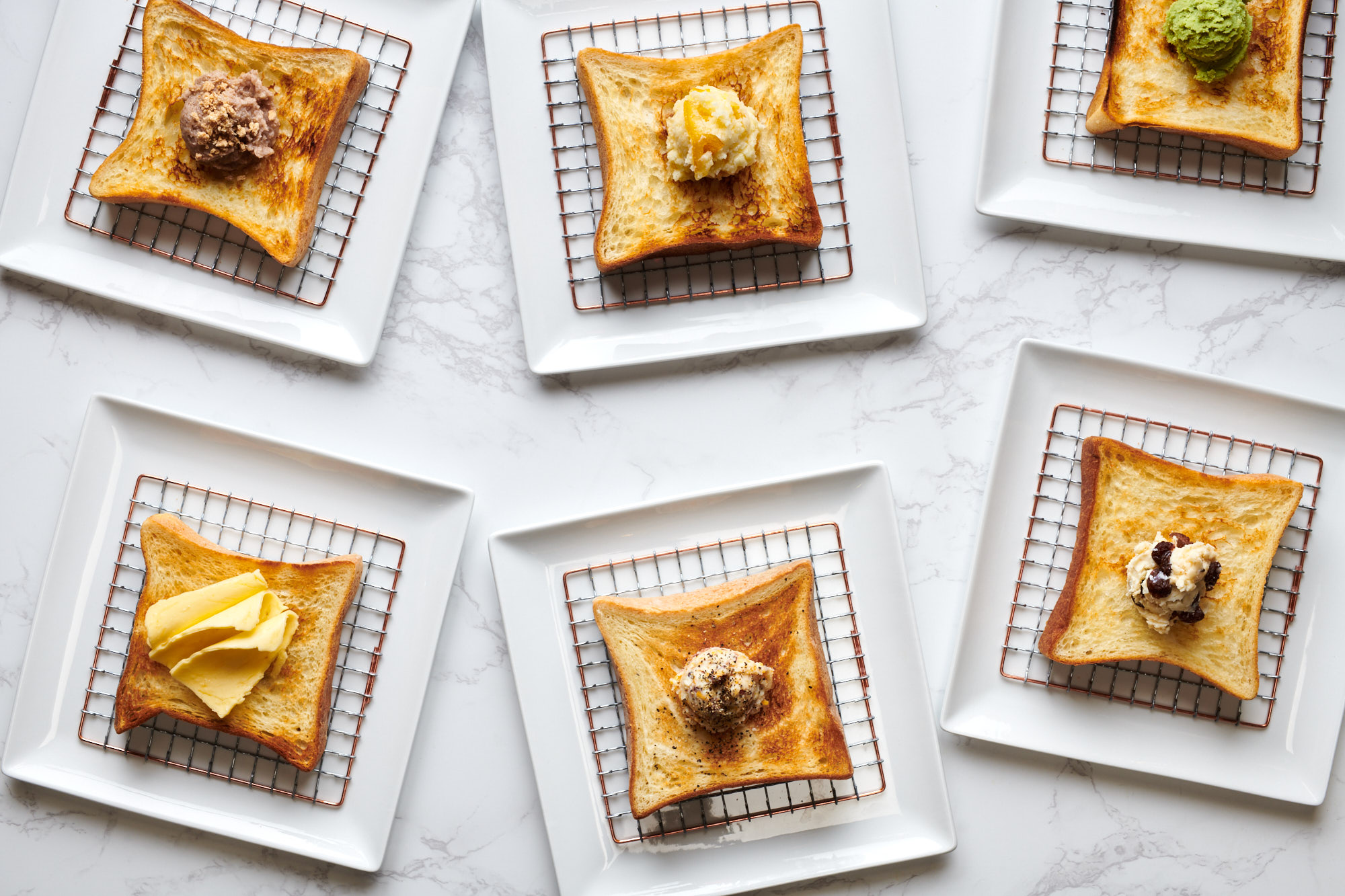 Six pieces of shokupan toast sit on a white marble counter under grates at Kimura Toast Bar