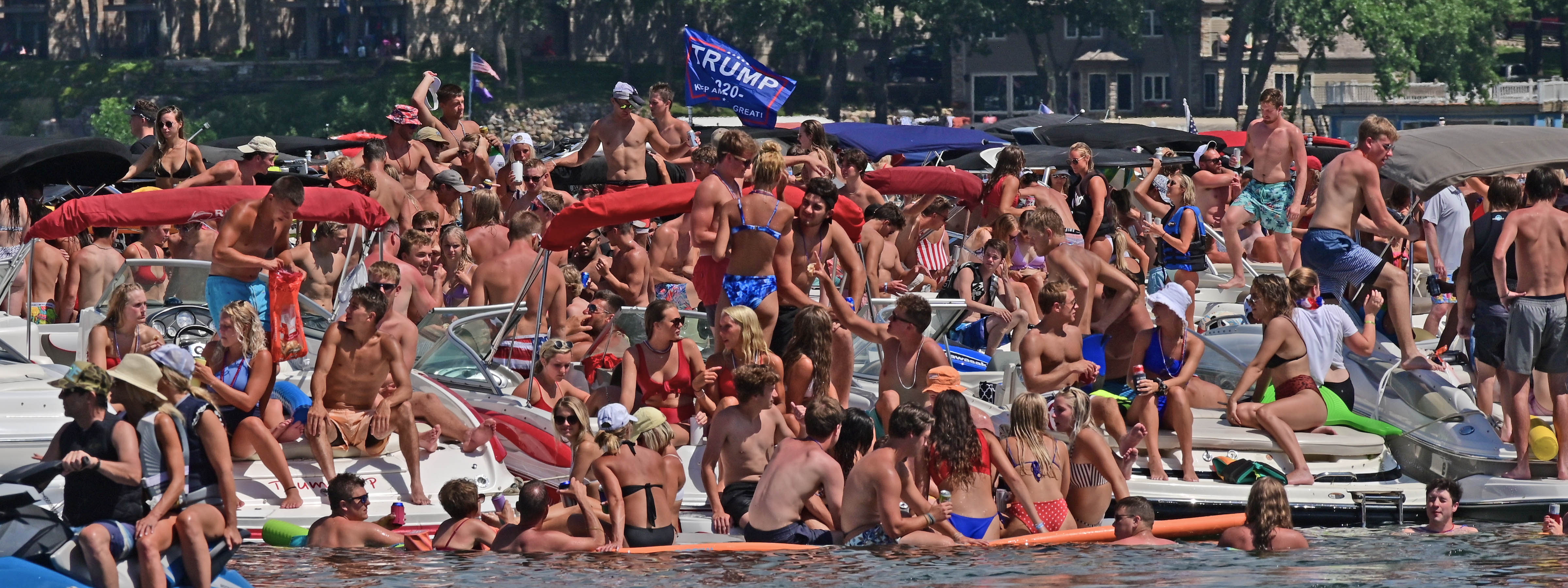 A crowd of people in bathing suits floating on rafts on a lake.