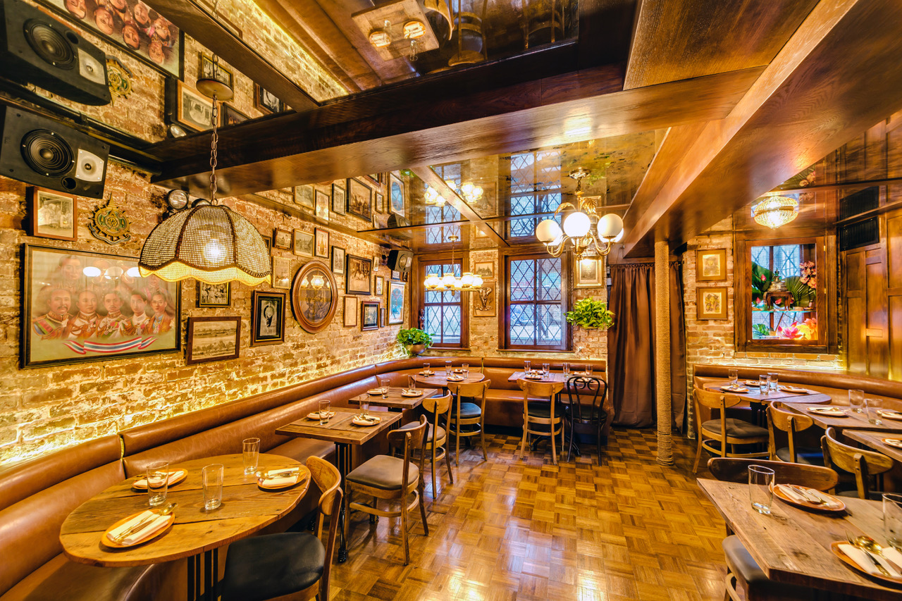 The interior of wood paneled restaurant with lots of photos on the wall and wooden dining tables and chairs
