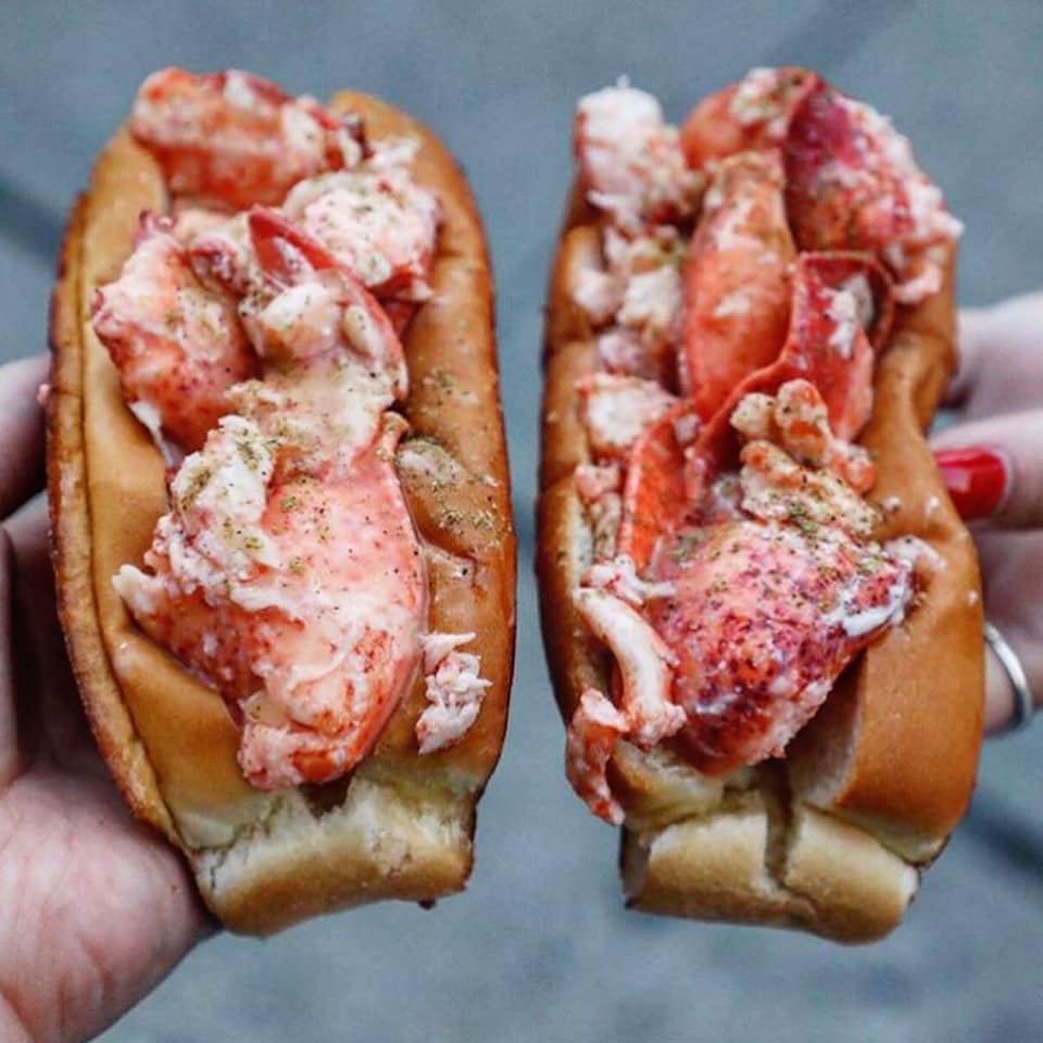 Two lobster rolls held in two hands