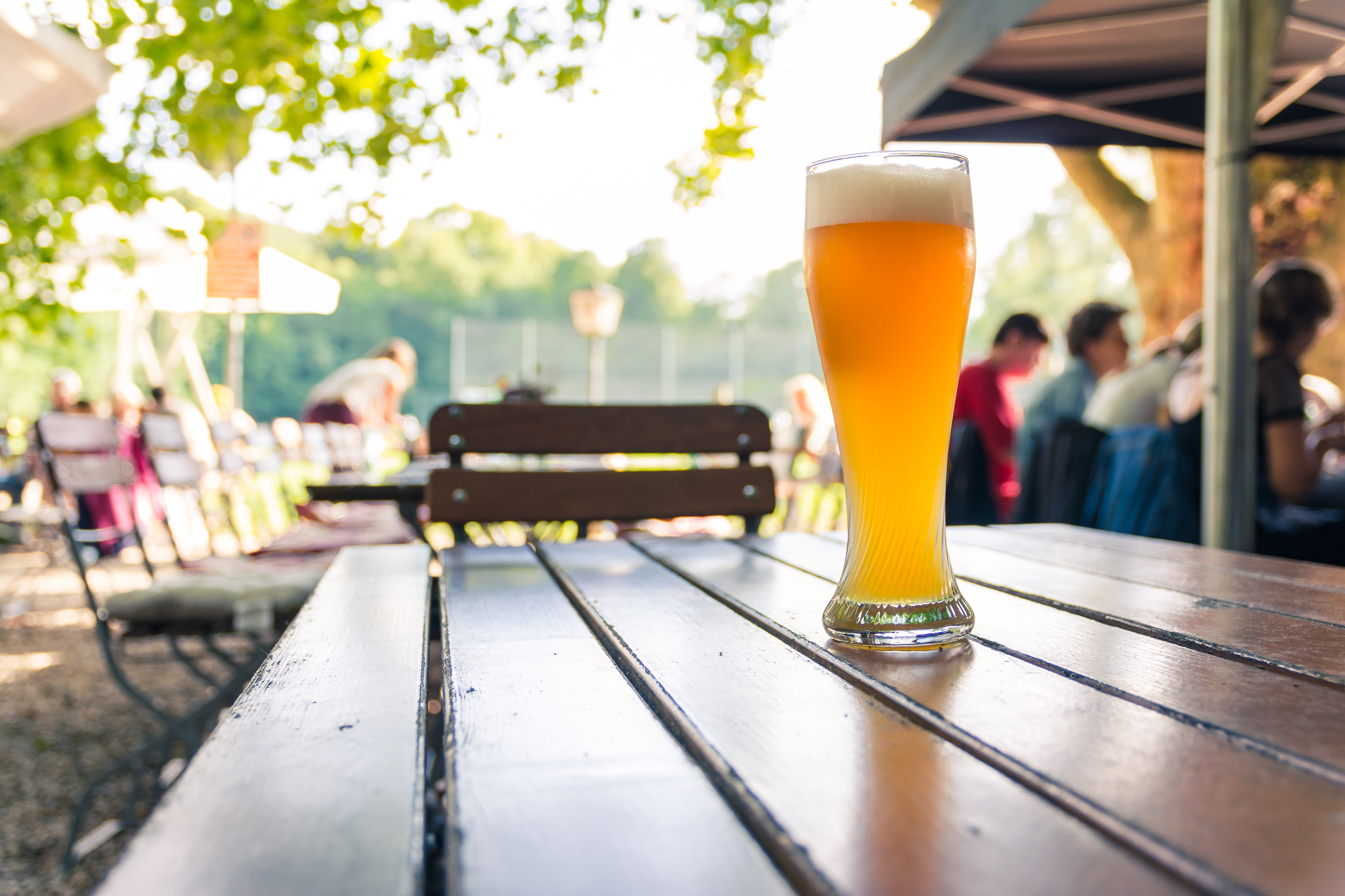 A stock photograph of a glass of beer on an outdoor table in a beer garden