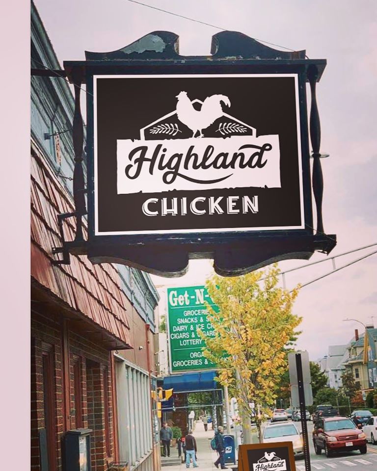 White text on black signage outside a restaurant reads “highland chicken,” with a chicken logo in white