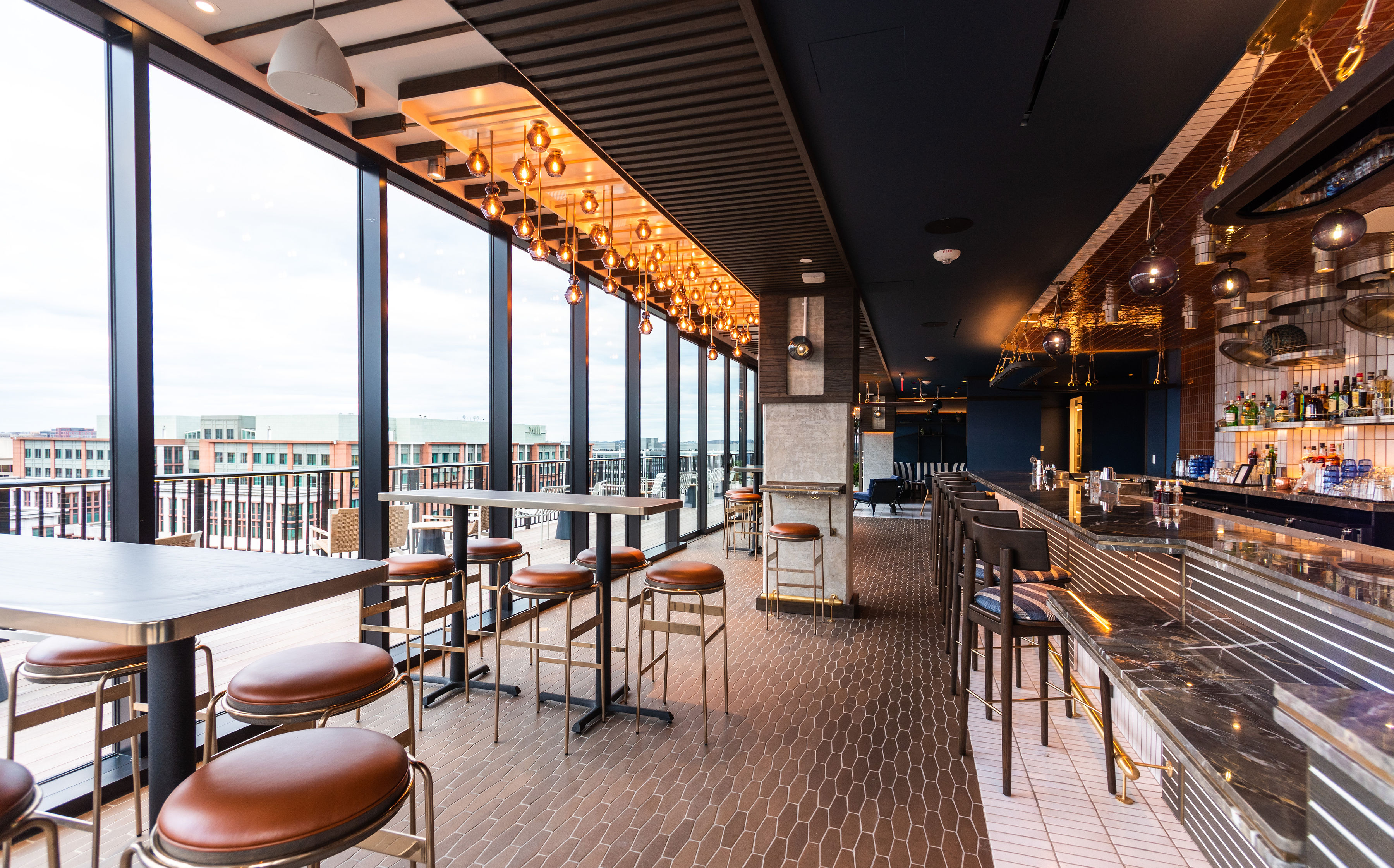 Wall-to-wall windows offer a view from a heated indoor space at the rooftop bar