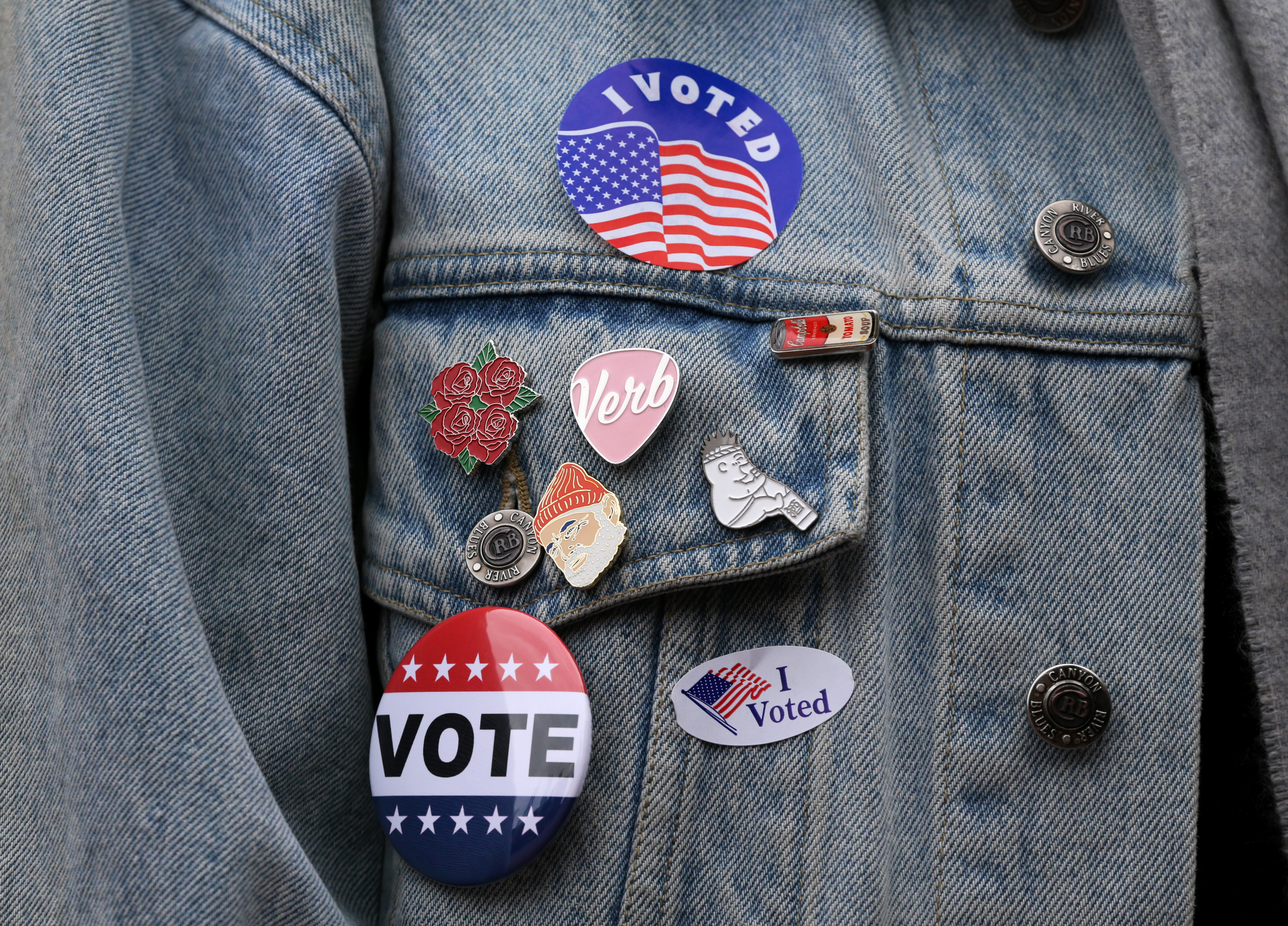A person poses voting stickers and pins.