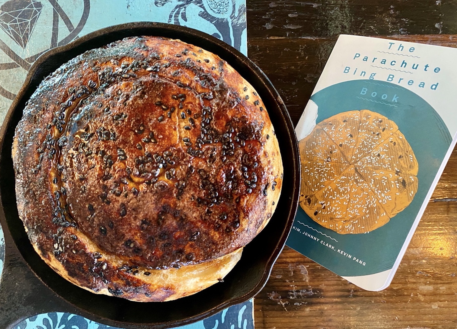 A cast iron pan filled with Bing bread, next to a book called, “The Parachute Bing Bread Book”