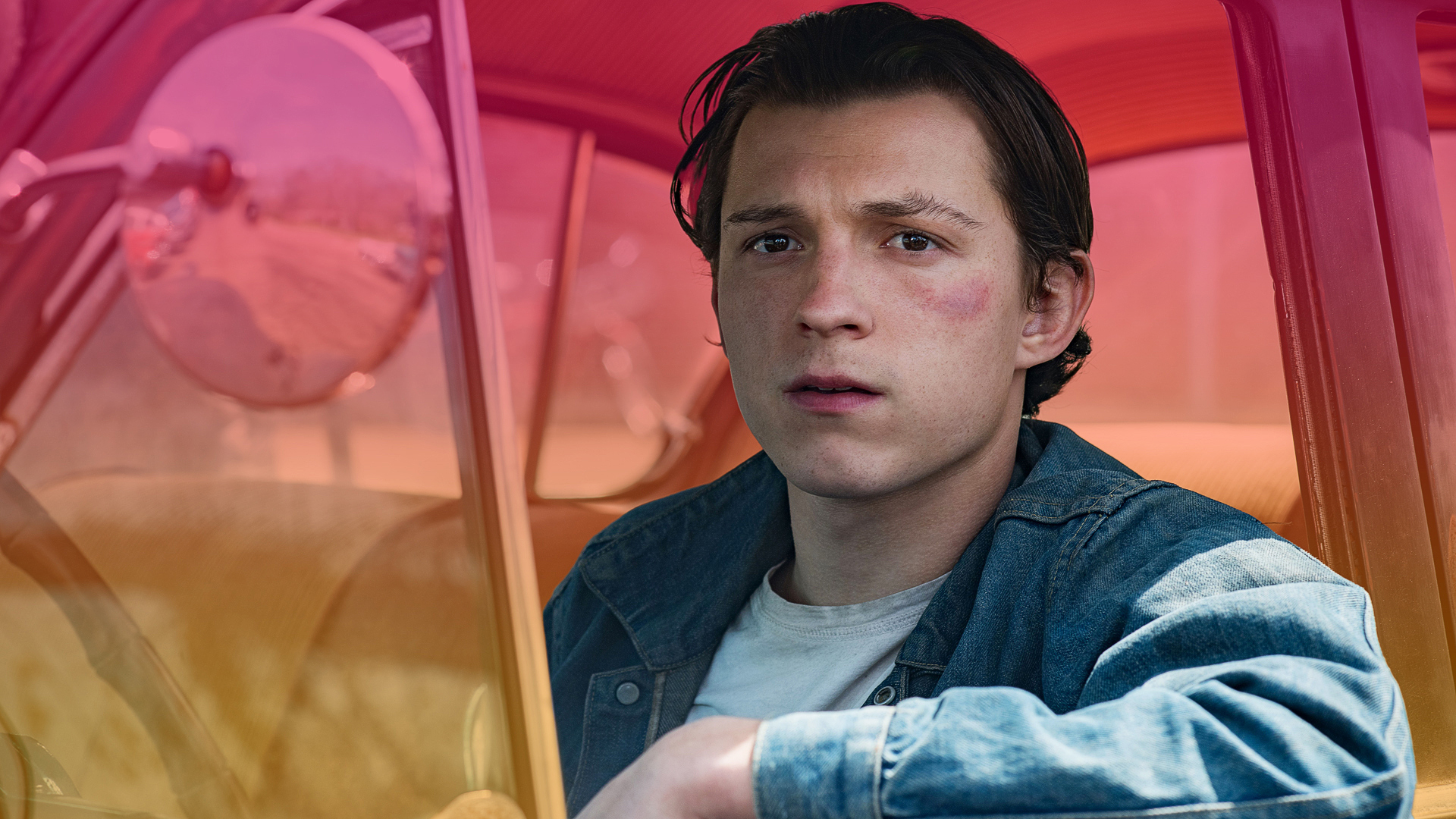Tom Holland looks out of an open car window in the movie The Devil All The Time