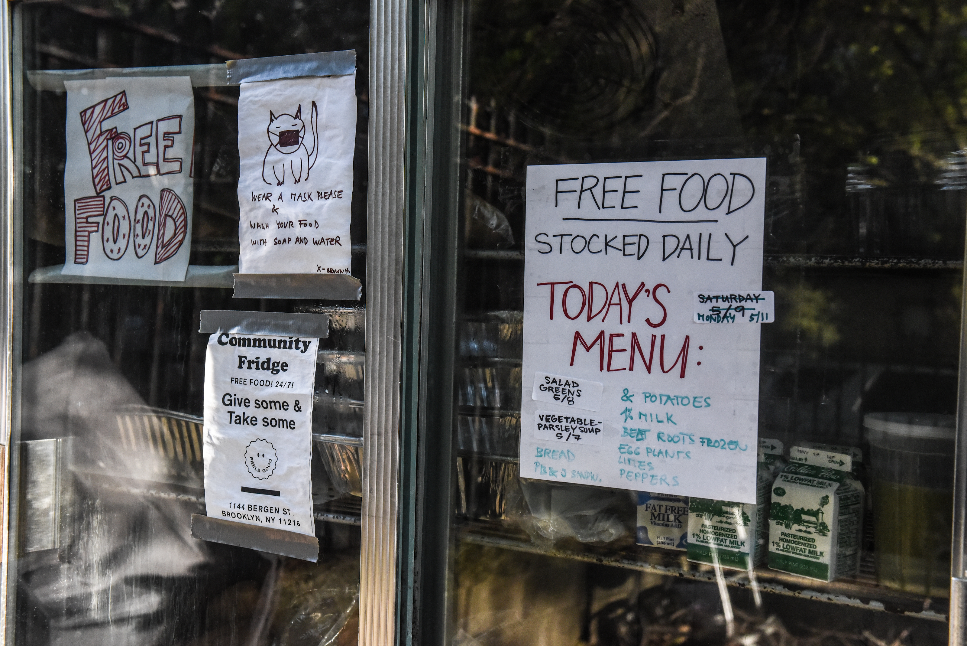 Signs reading “free food” and “today’s menu” are posted to the sliding glass doors of a well-stocked industrial fridge.