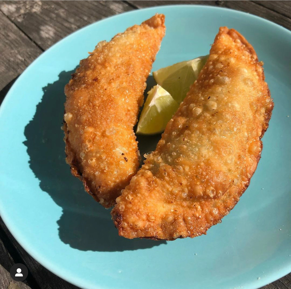 Two empanadas sit on a blue table with two lines