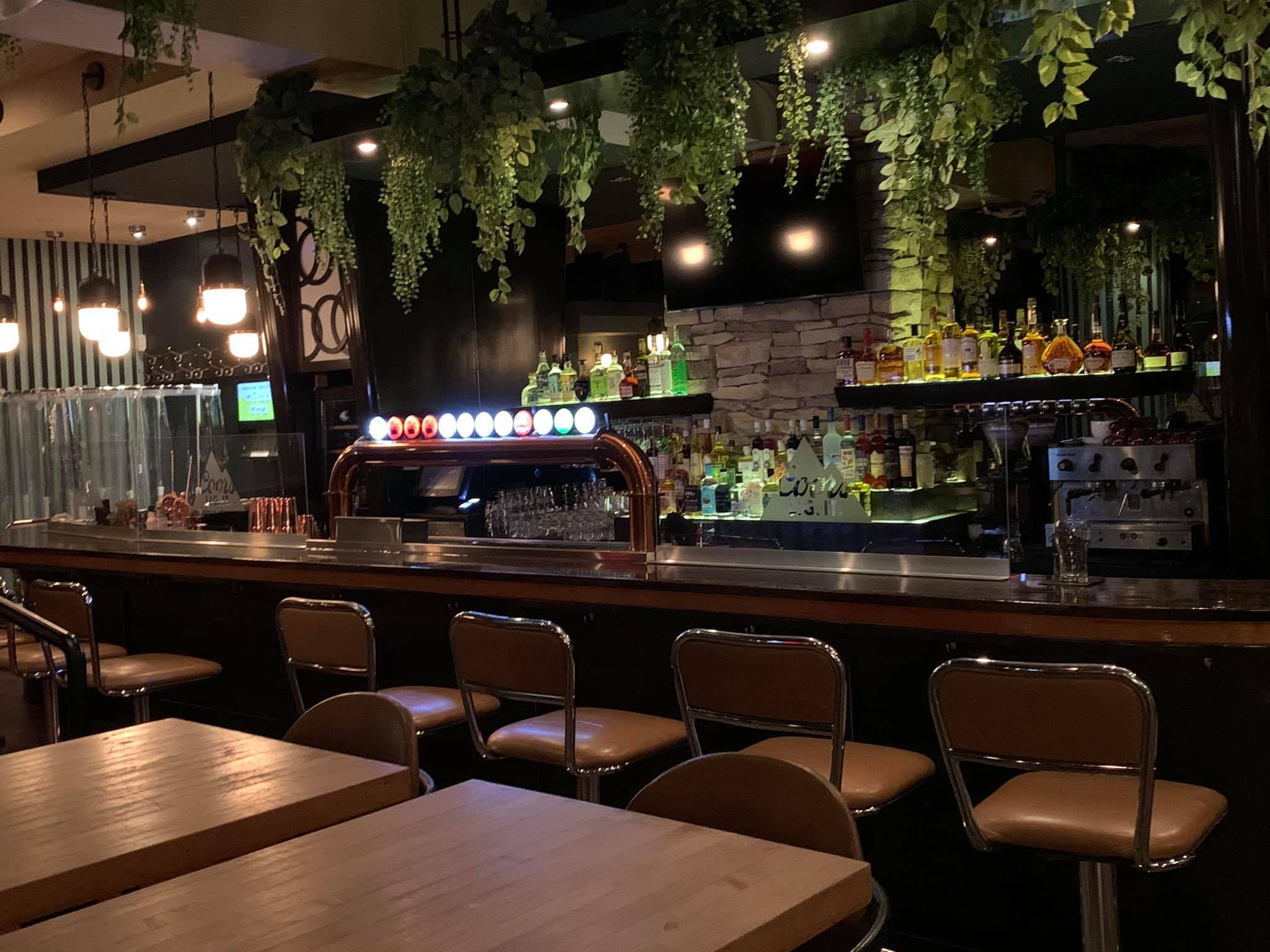 Bar with five stools and greenery.