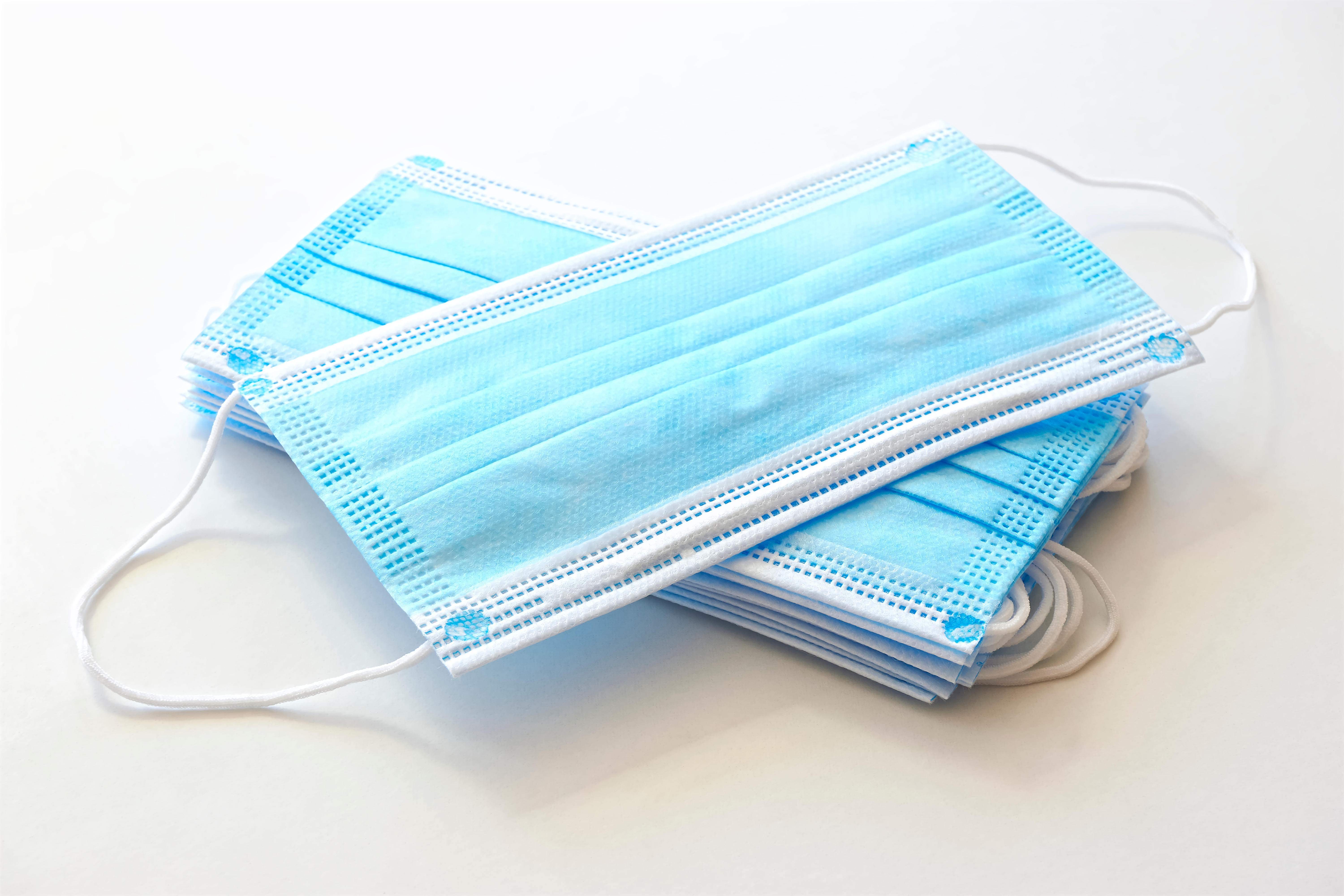 Two piles of blue face coverings criss-cross against a white background.