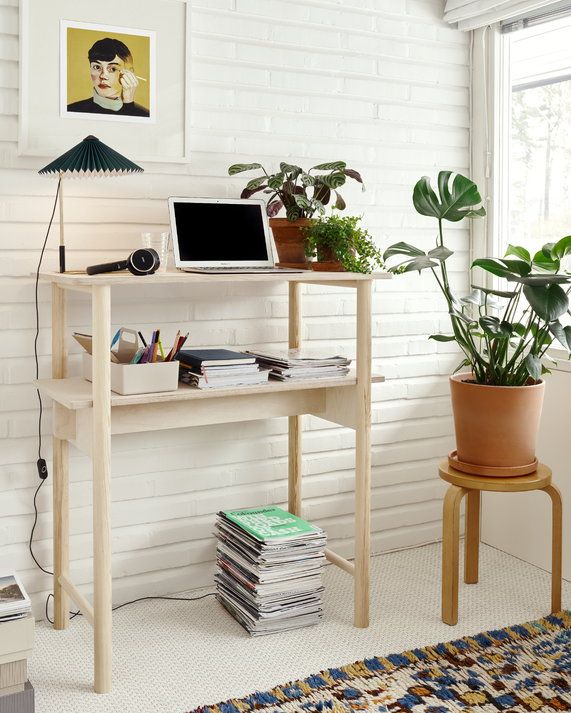 Blonde wood standing desk surrounded by plants.