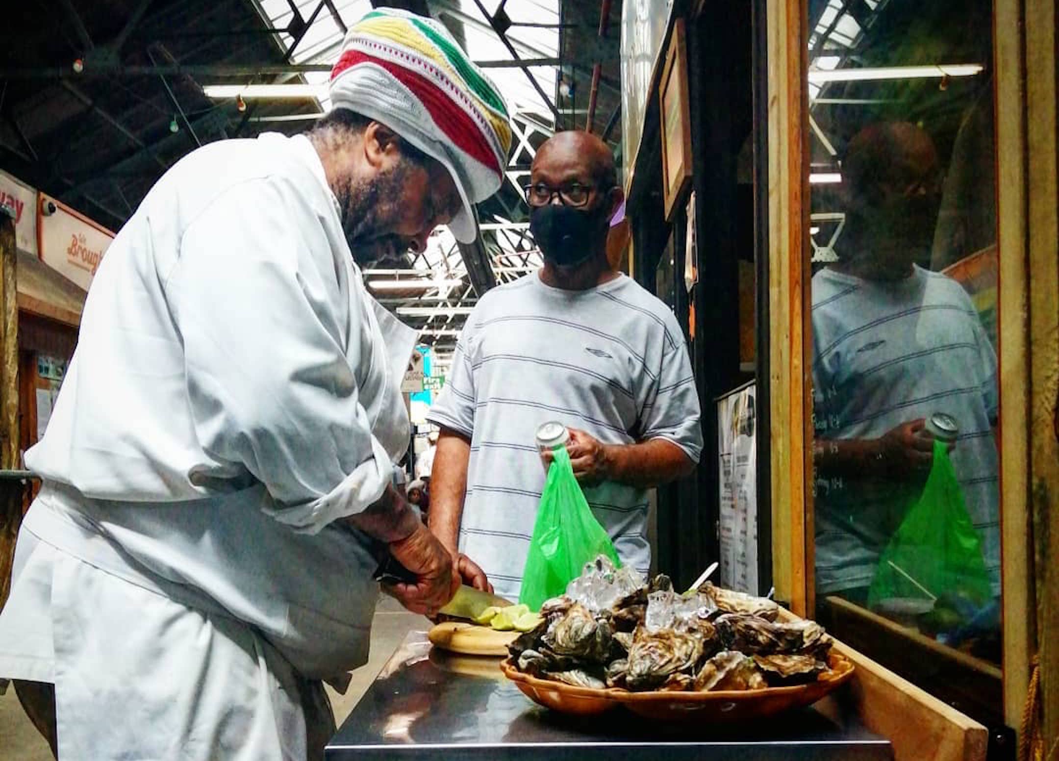 Christopher preparing oysters at The Lone Fisherman in Tooting Market, with a customer waiting