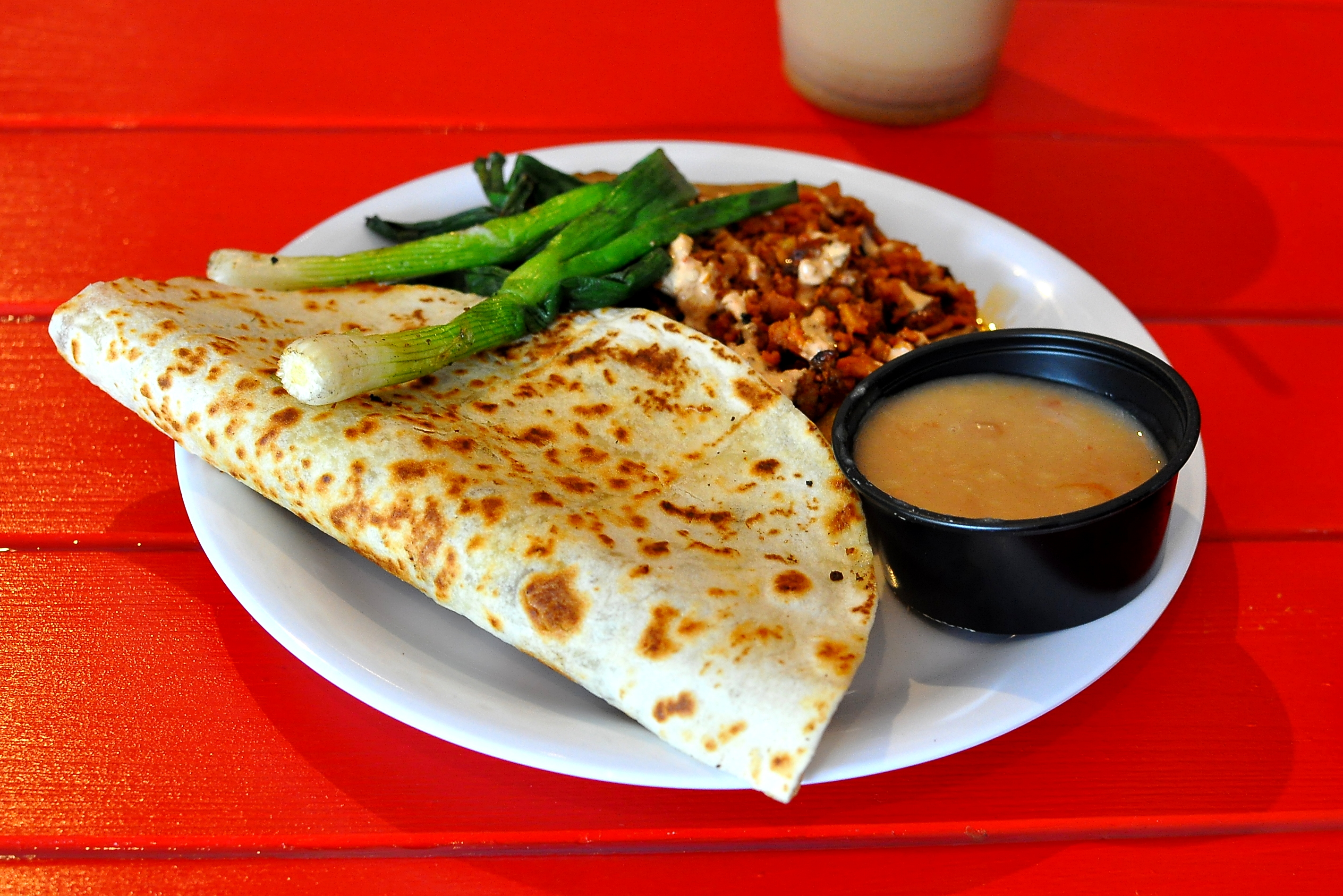 A quesadilla and vampiro on a bright red table at a Mexican restaurant.