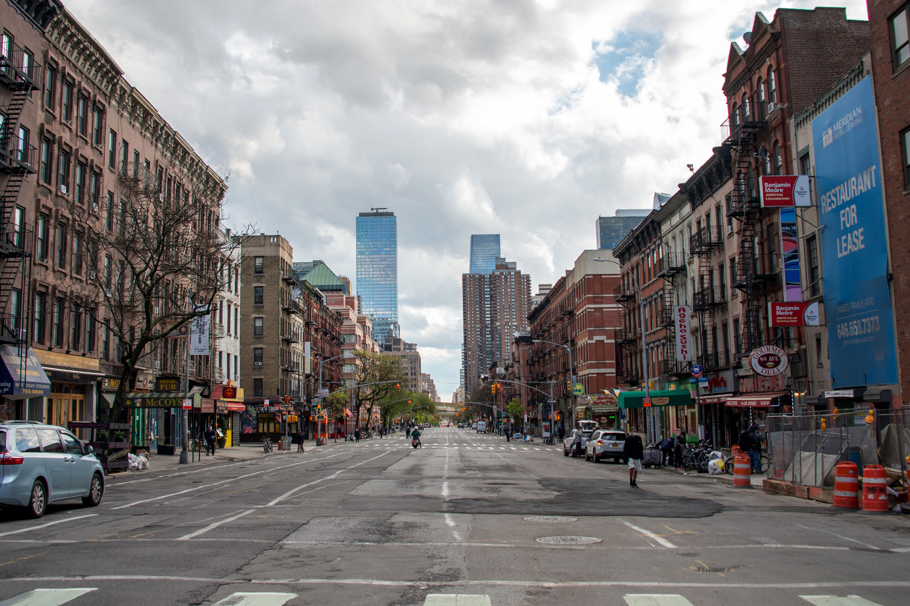 纽约市一条空荡荡的街道两旁都是建筑物，天空乌云密布。这张图片展示了冠状病毒大流行期间纽约市的购车状况。