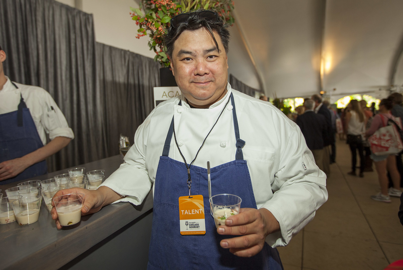 A chef poses with an apron and drinks in his hands.