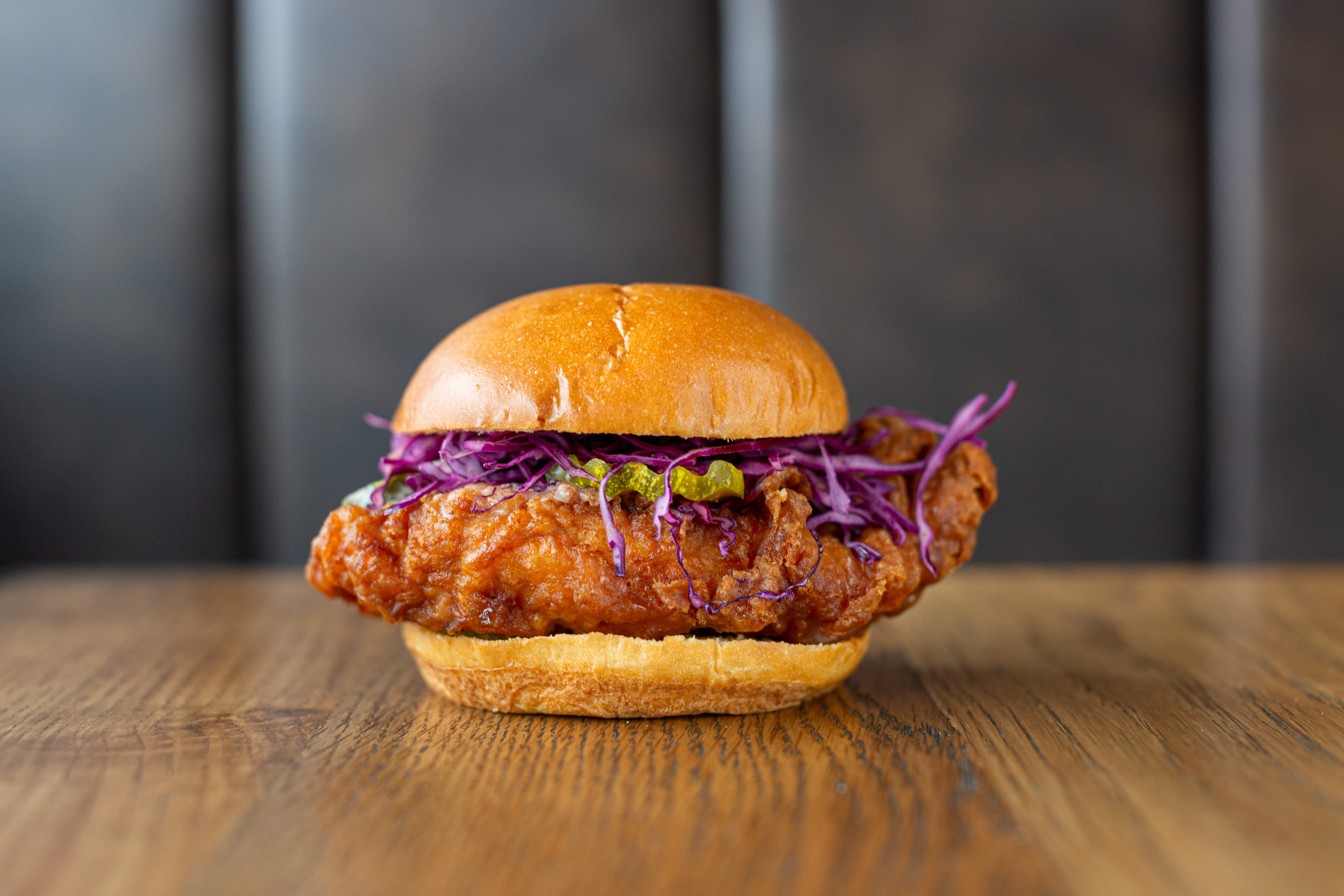 A fried chicken sandwich on brioche with purple cabbage.