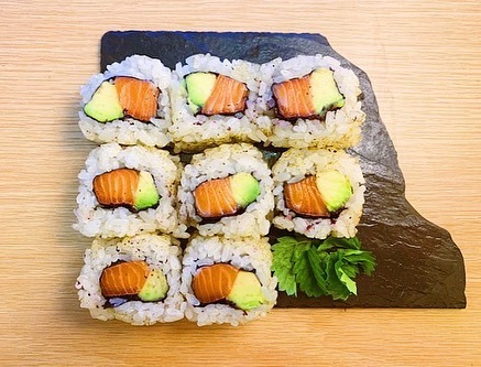 Eight sushi rolls wrapped in rice with the fish and avocado visible inside