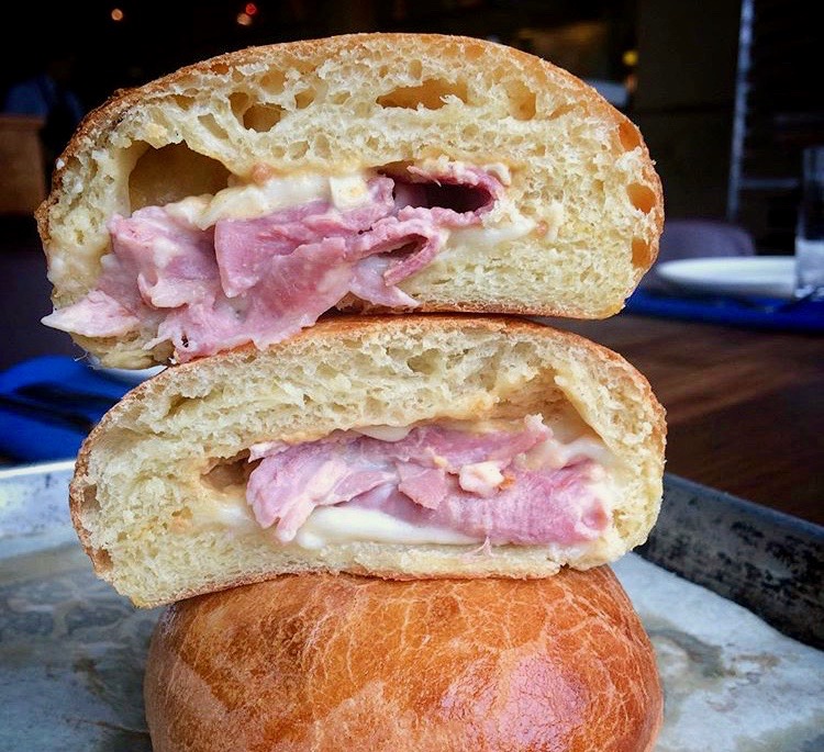 baked bun stuffed with ham and cheese cut open