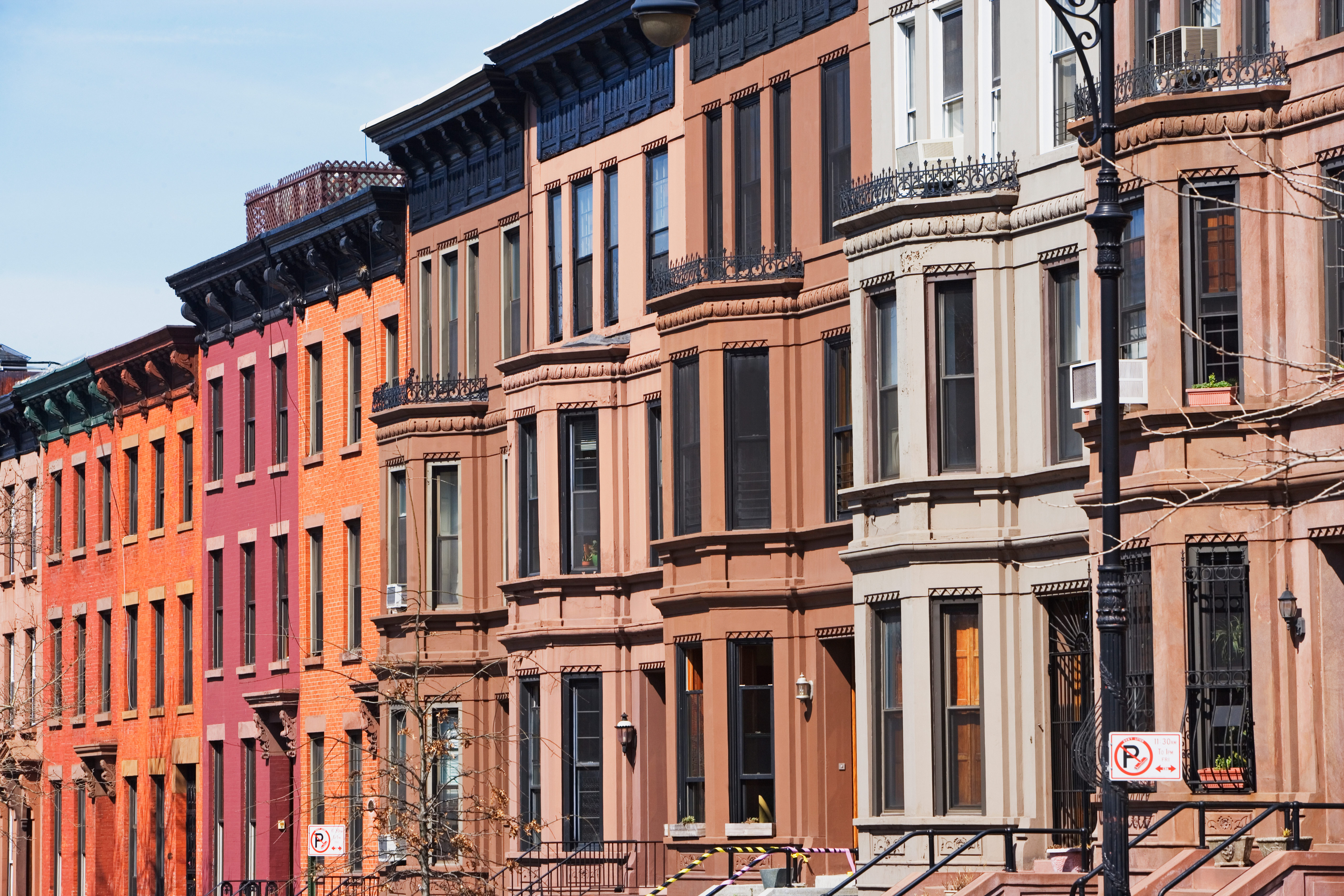 A row of brownstones and bright brick apartment buildings on a block in Brooklyn.