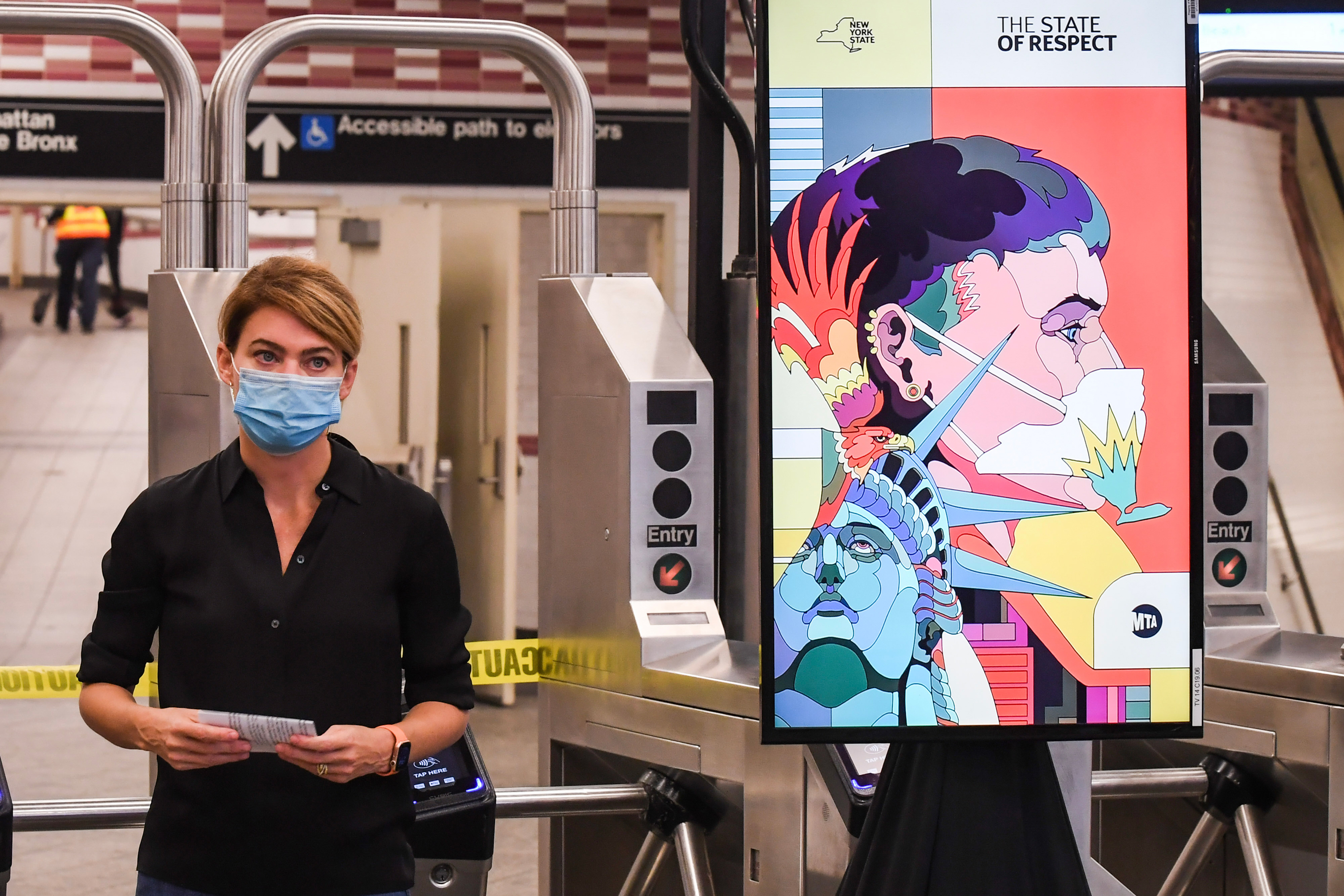 New York City Transit President Sarah Feinberg stands next to a video screen Atlantic Avenue-Barclays station in Brooklyn during a news conference to promote mask wearing, Sept. 14, 2020.