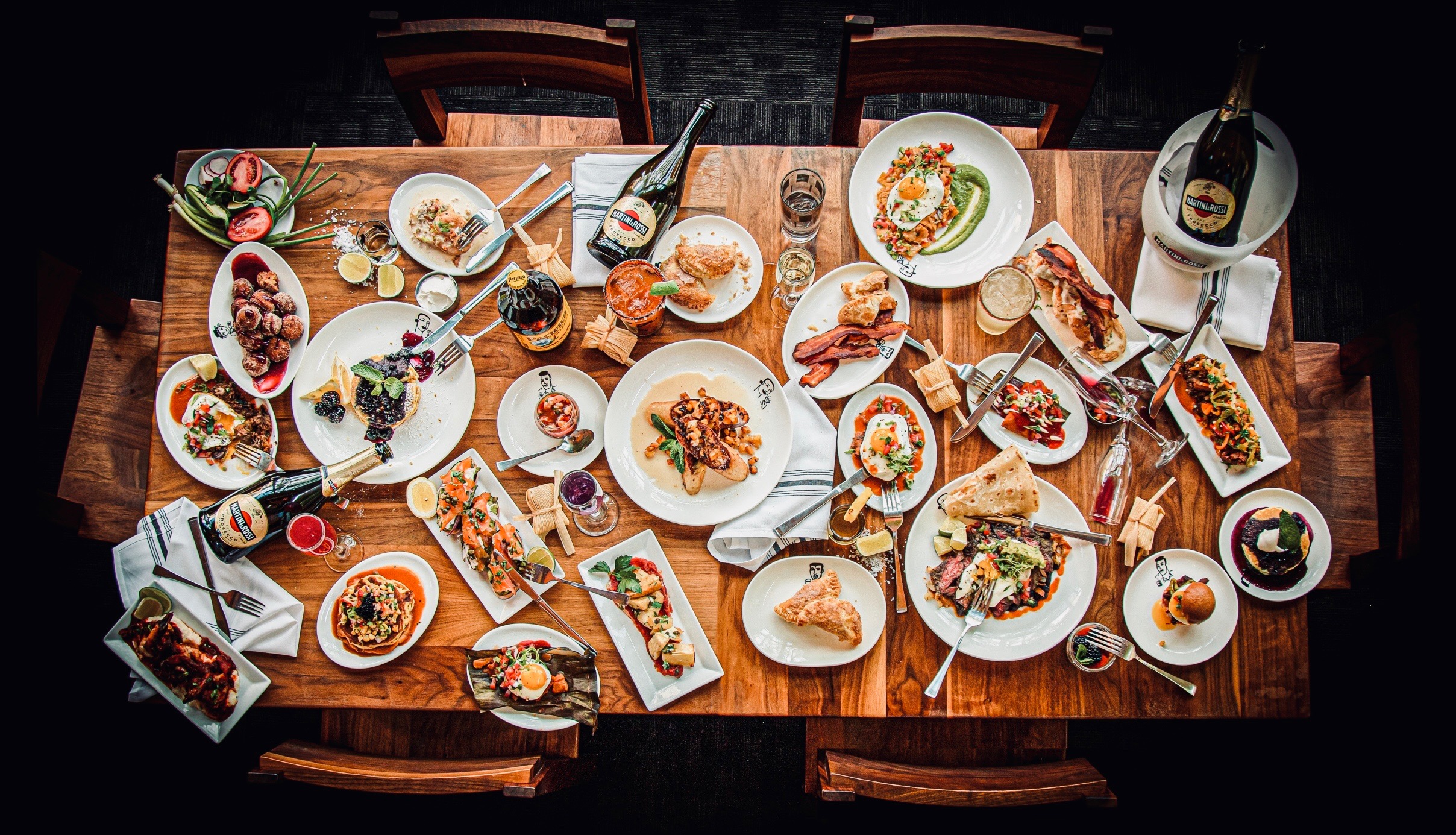 A rectangular wood table filled with brunch dishes on white plates.