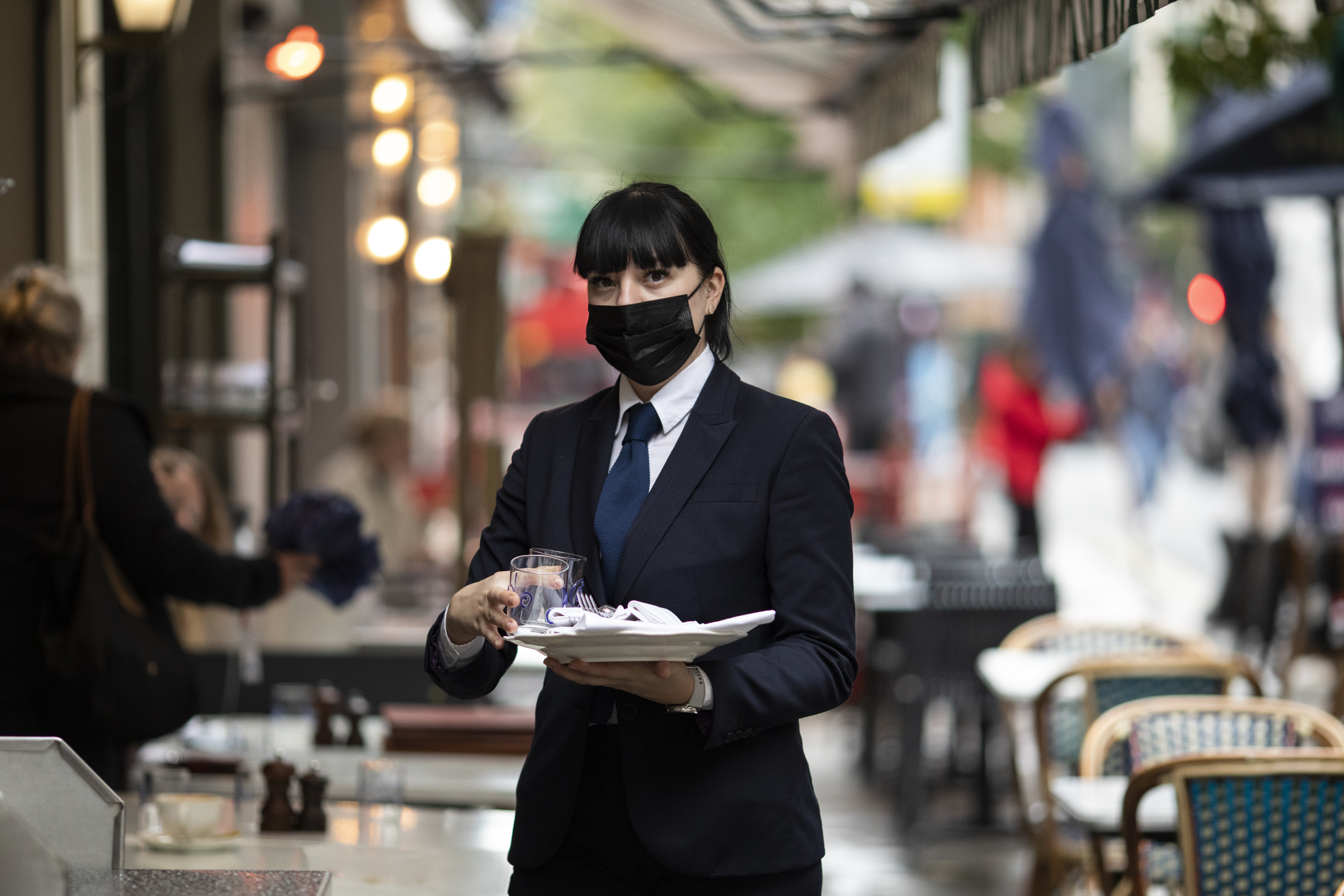 A waiter in a mask outside a London restaurant