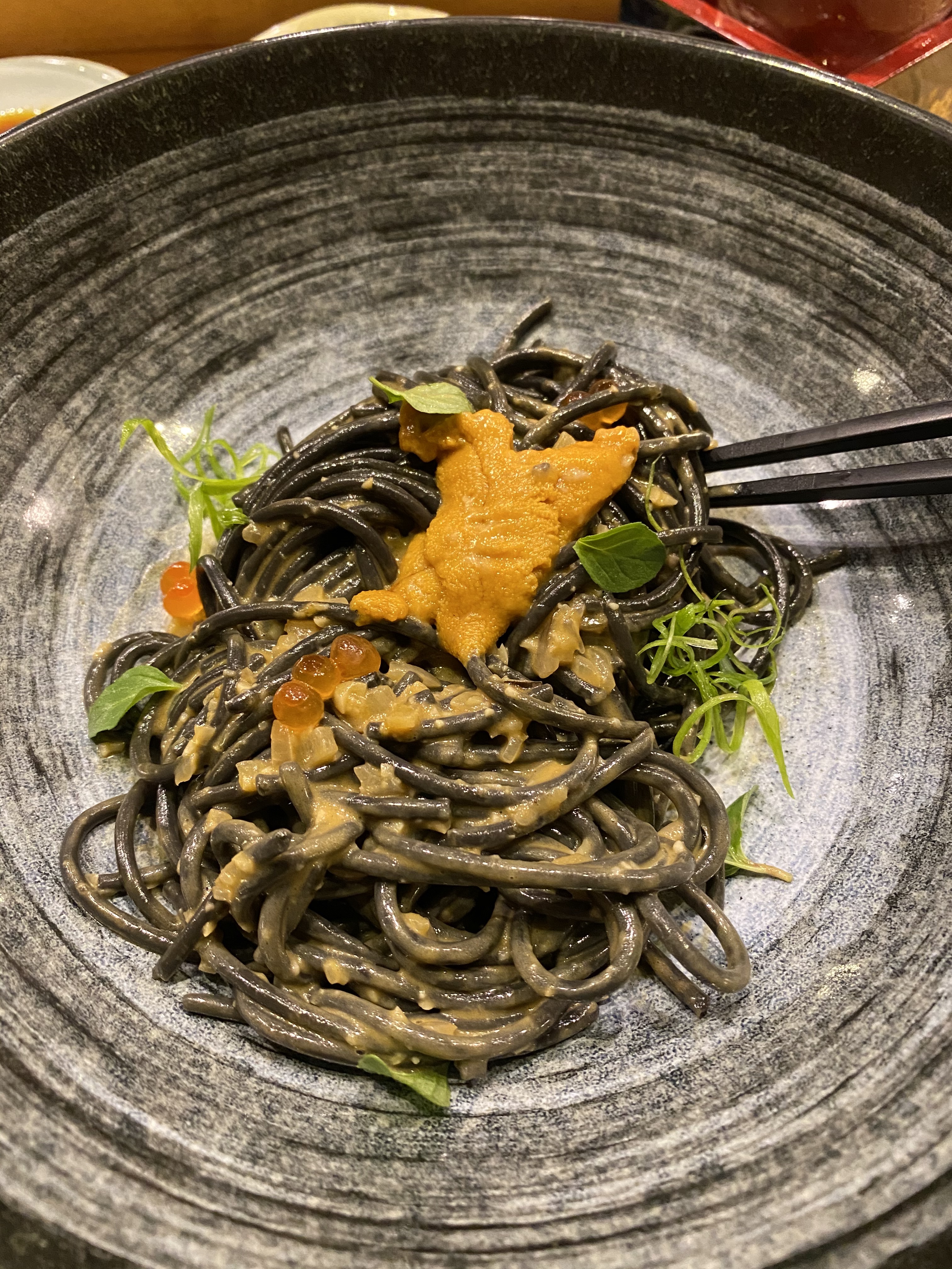 Squid ink pasta comes with a bright-orange uni butter with dots of salmon roe