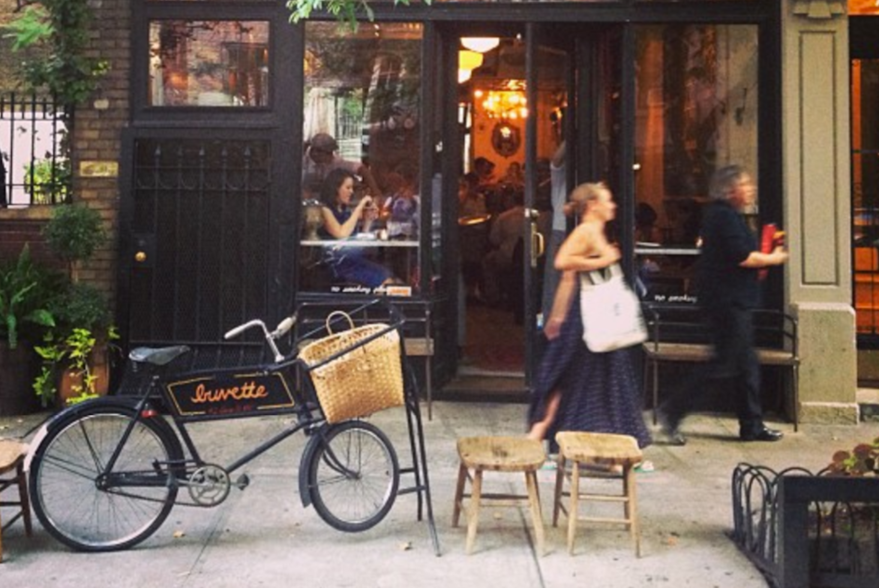 The exterior of Buvette NYC, with a bike parked outside and warm light in the windows 