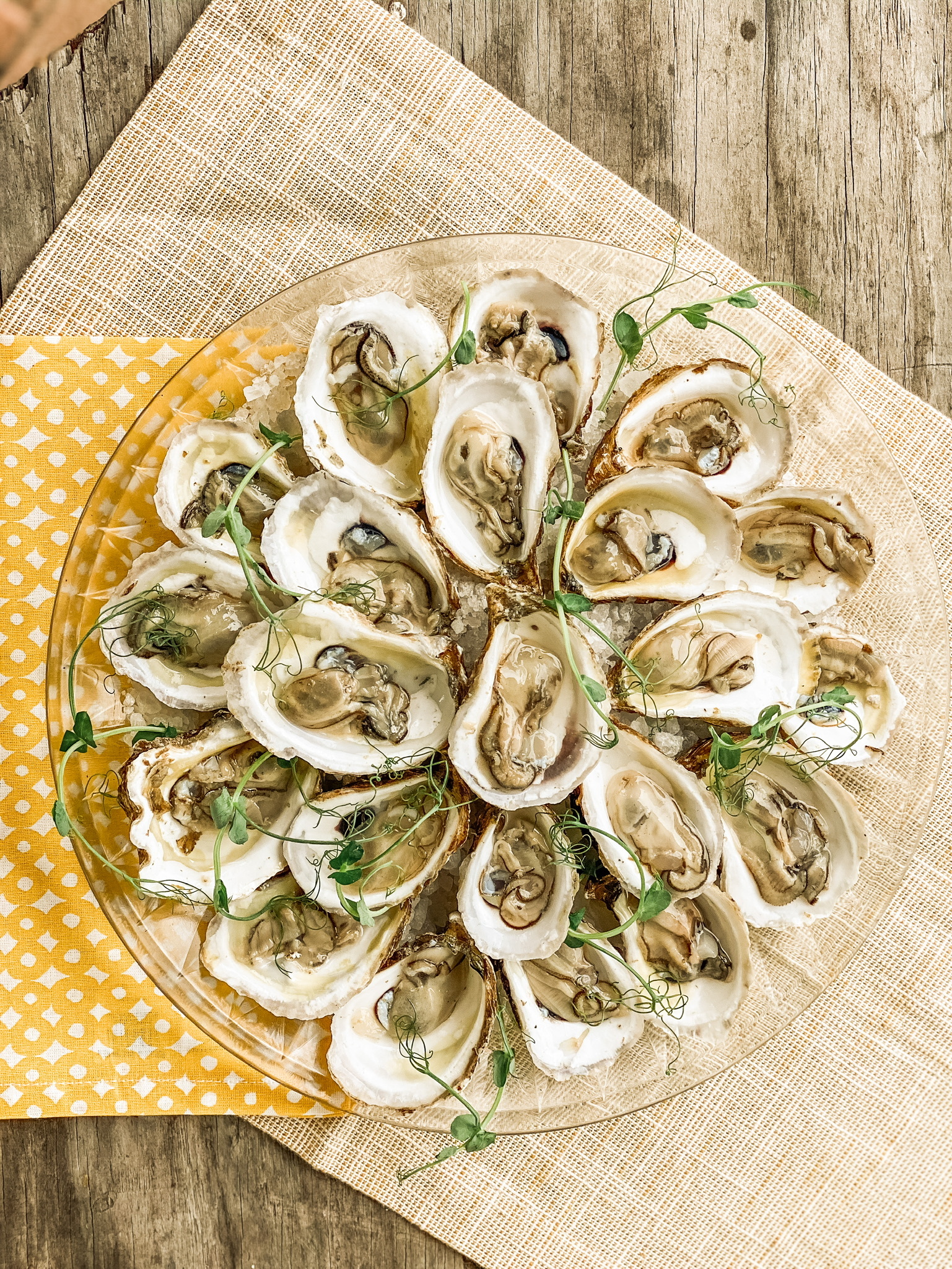 An overhead view of a plate of raw oysters garnished with shaved spring onions.