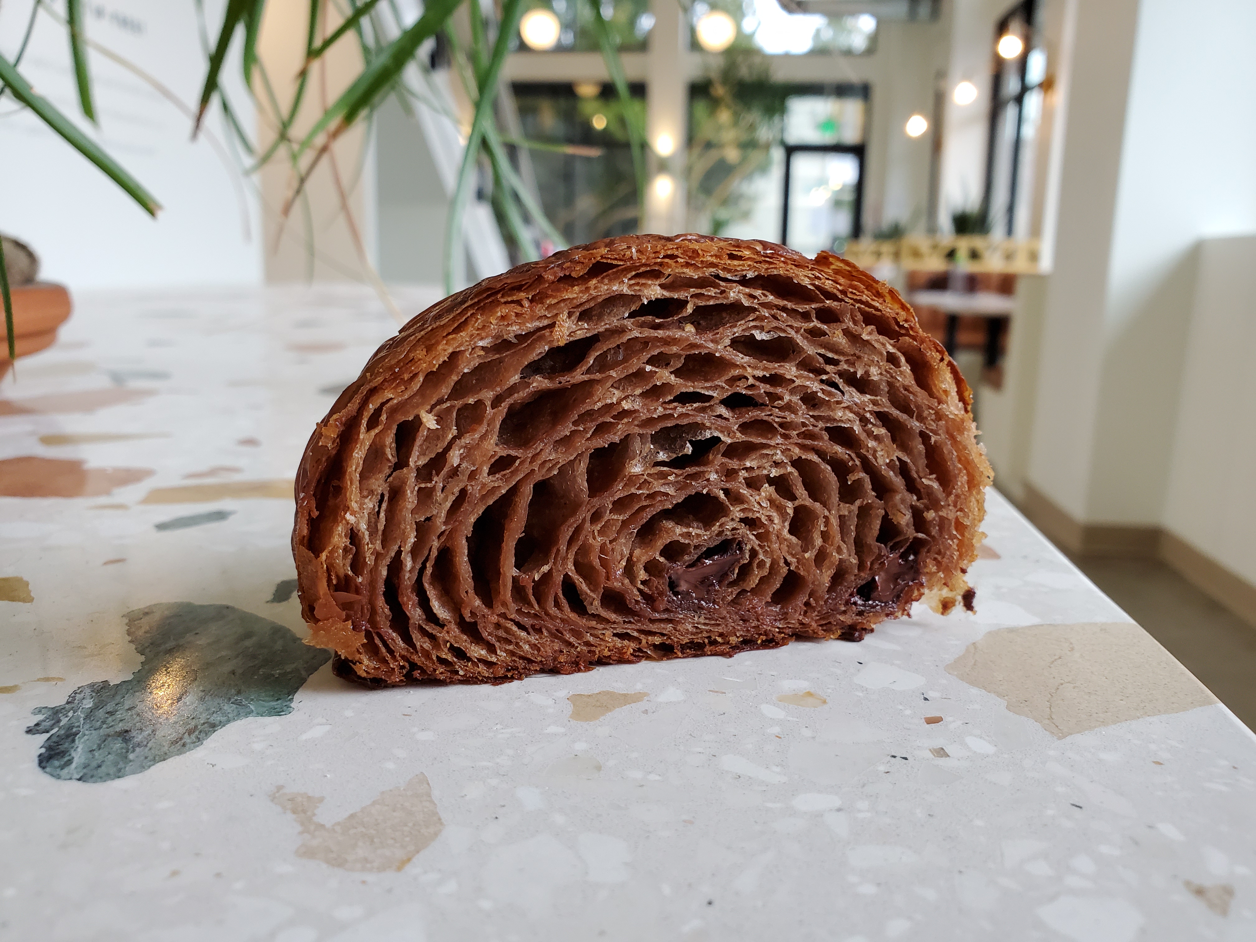 A closeup of a buckwheat croissant, shown as a cross-section on a marble countertop