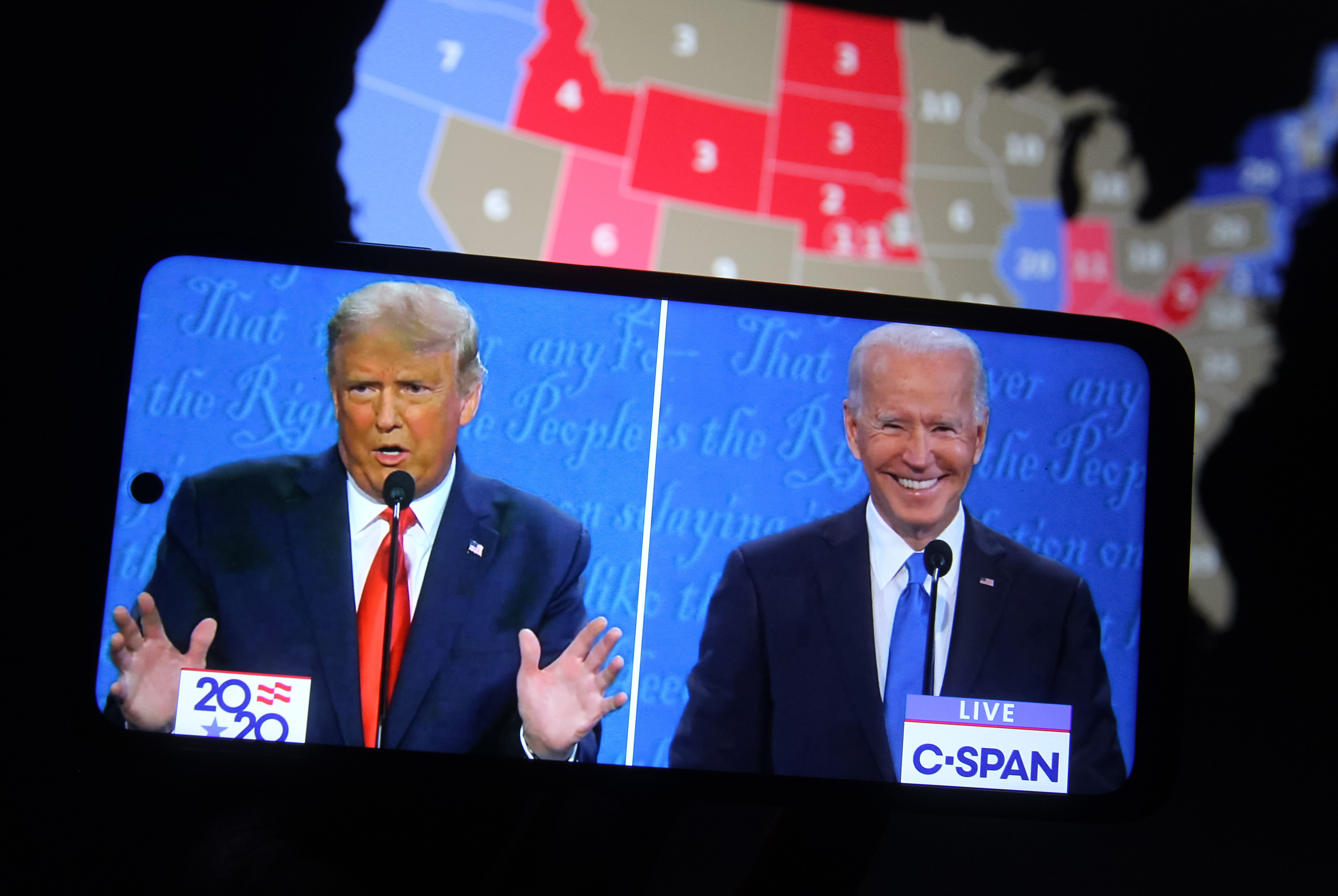 A photo illustration of President Donald Trump and Democratic presidential candidate Joe Biden on a smartphone screen, in front of an electoral map.