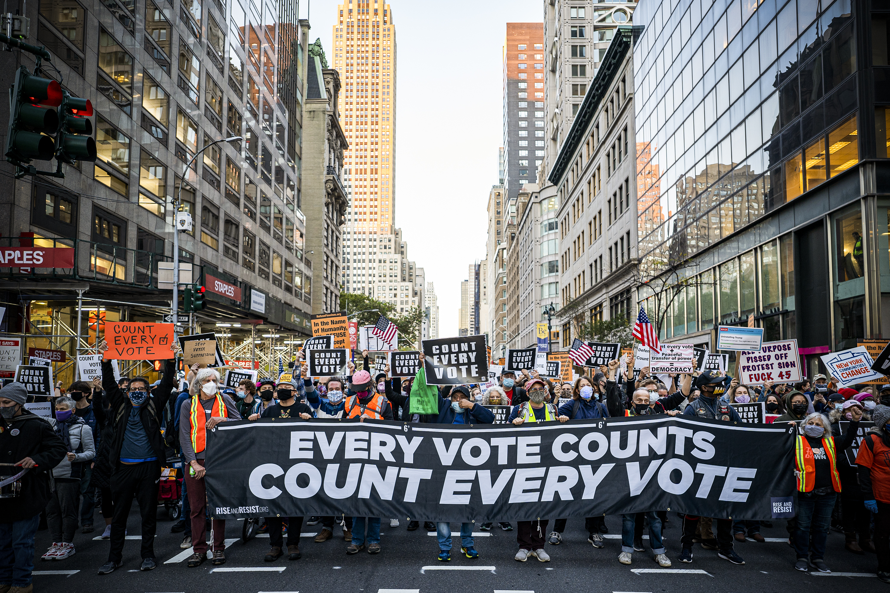 Protesters fill a city street carrying a sign reading, “Every vote counts. Count every vote.”
