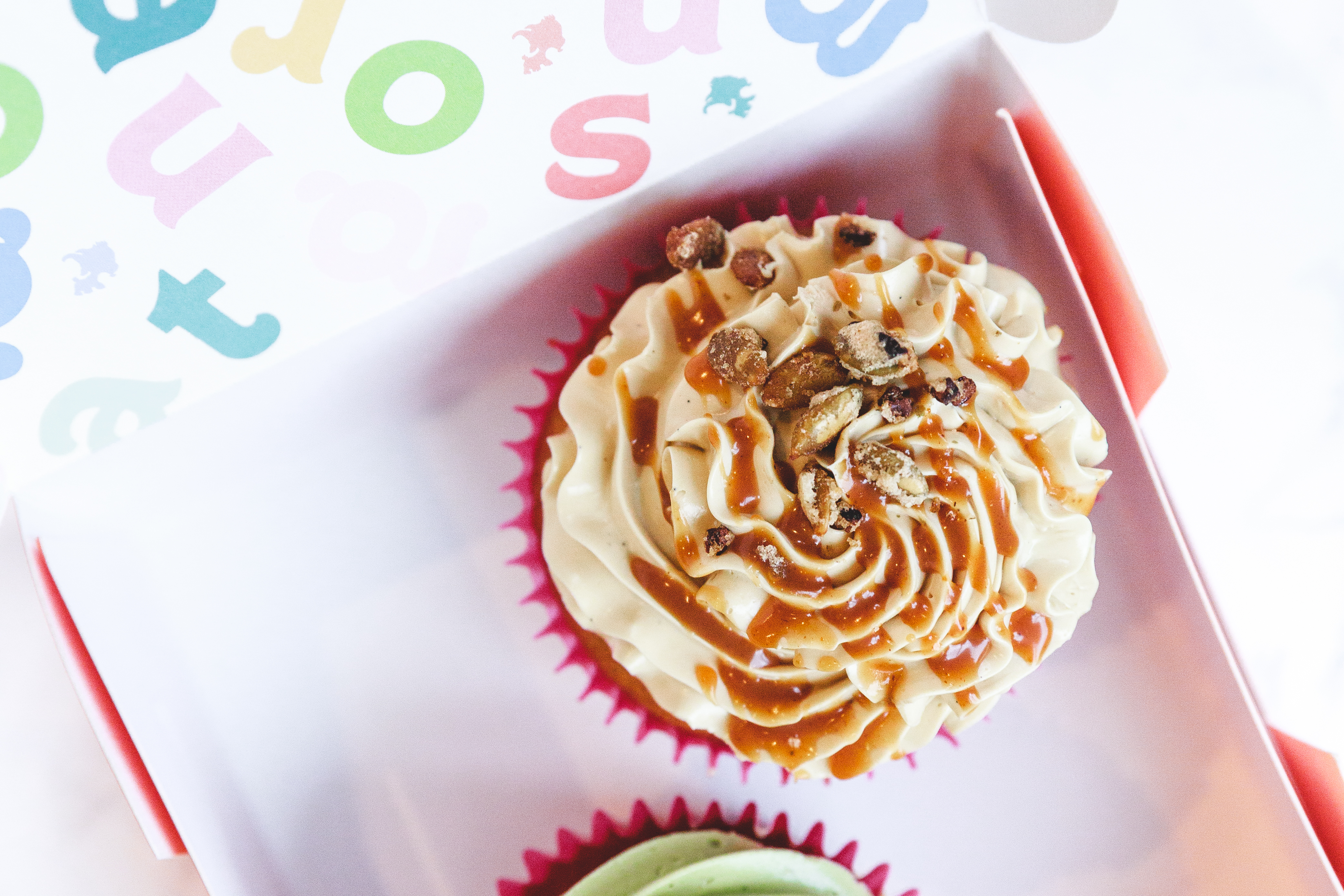 A cupcake topped with frosting and sauce inside a box.