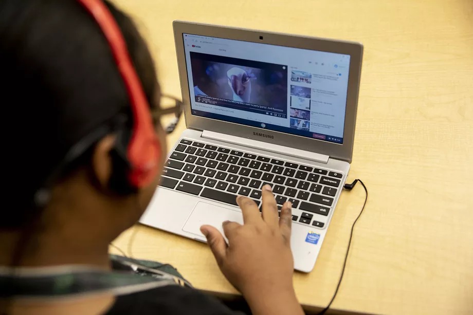A student wearing headphones works on a laptop computer during a special education classroom exercise.