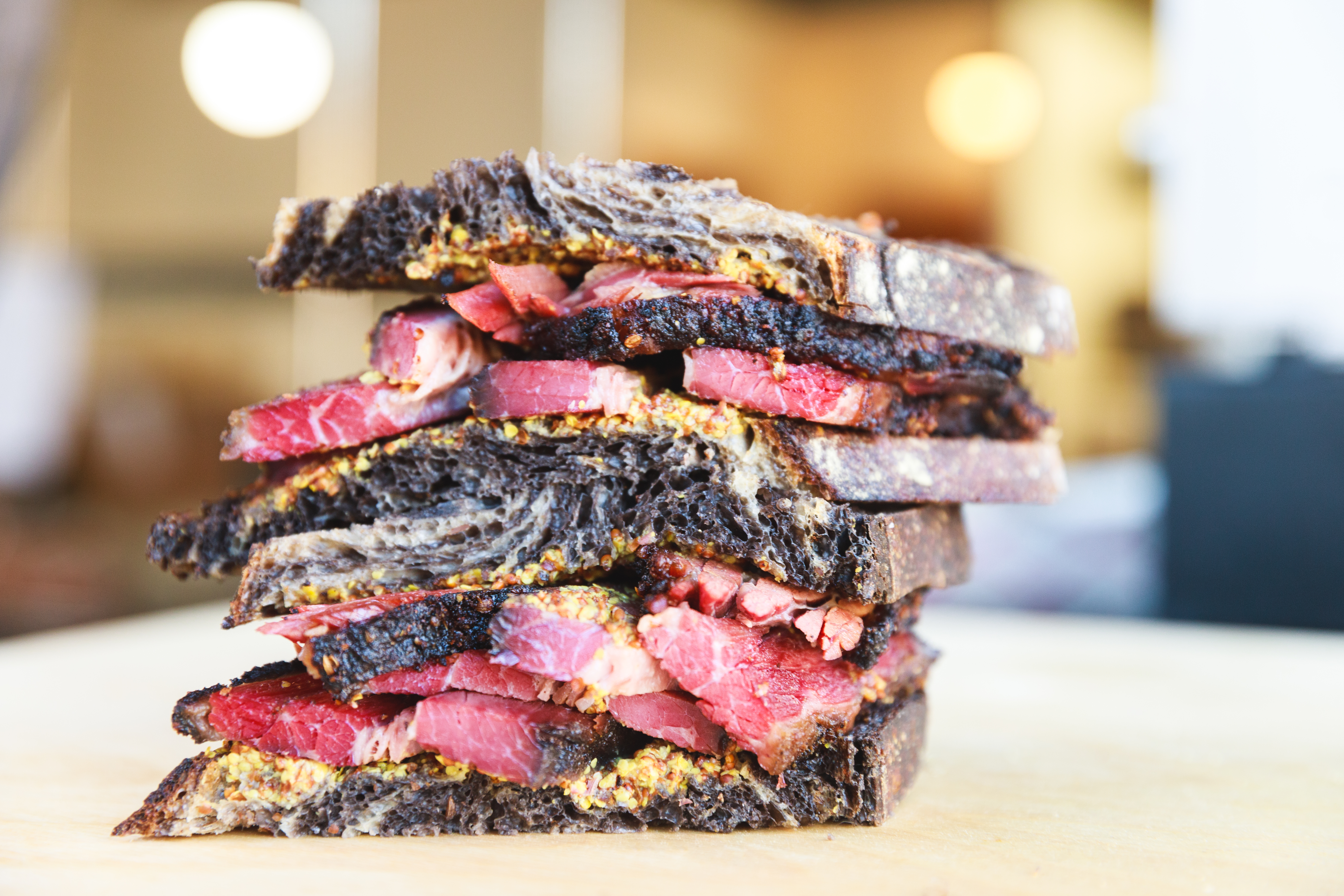 Two thick pastrami sandwiches stacked on top of each other.