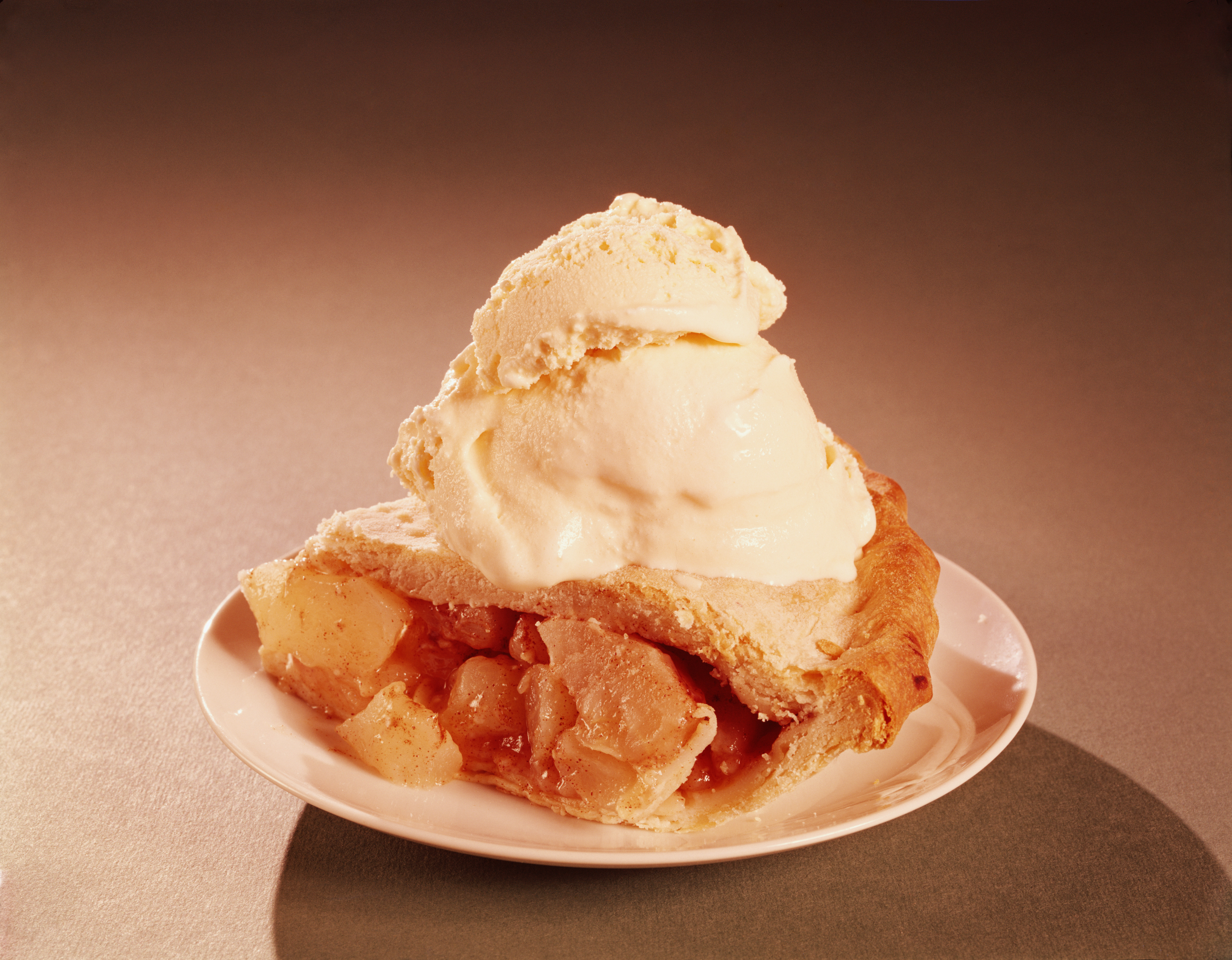 Retro-style image of a slice of apple pie with vanilla ice cream on top, on a plate.