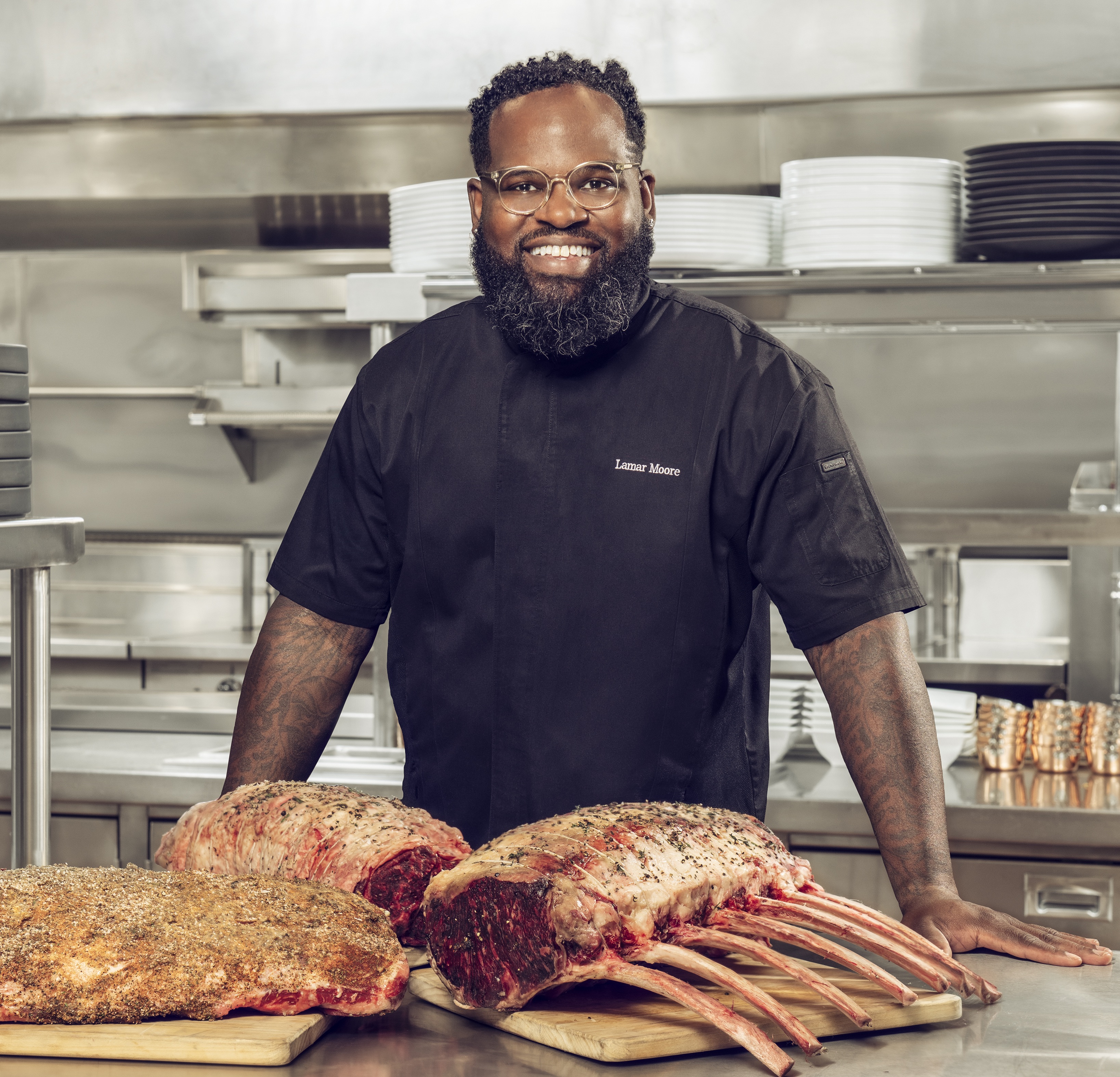 A chef stands in front of meat in a kitchen