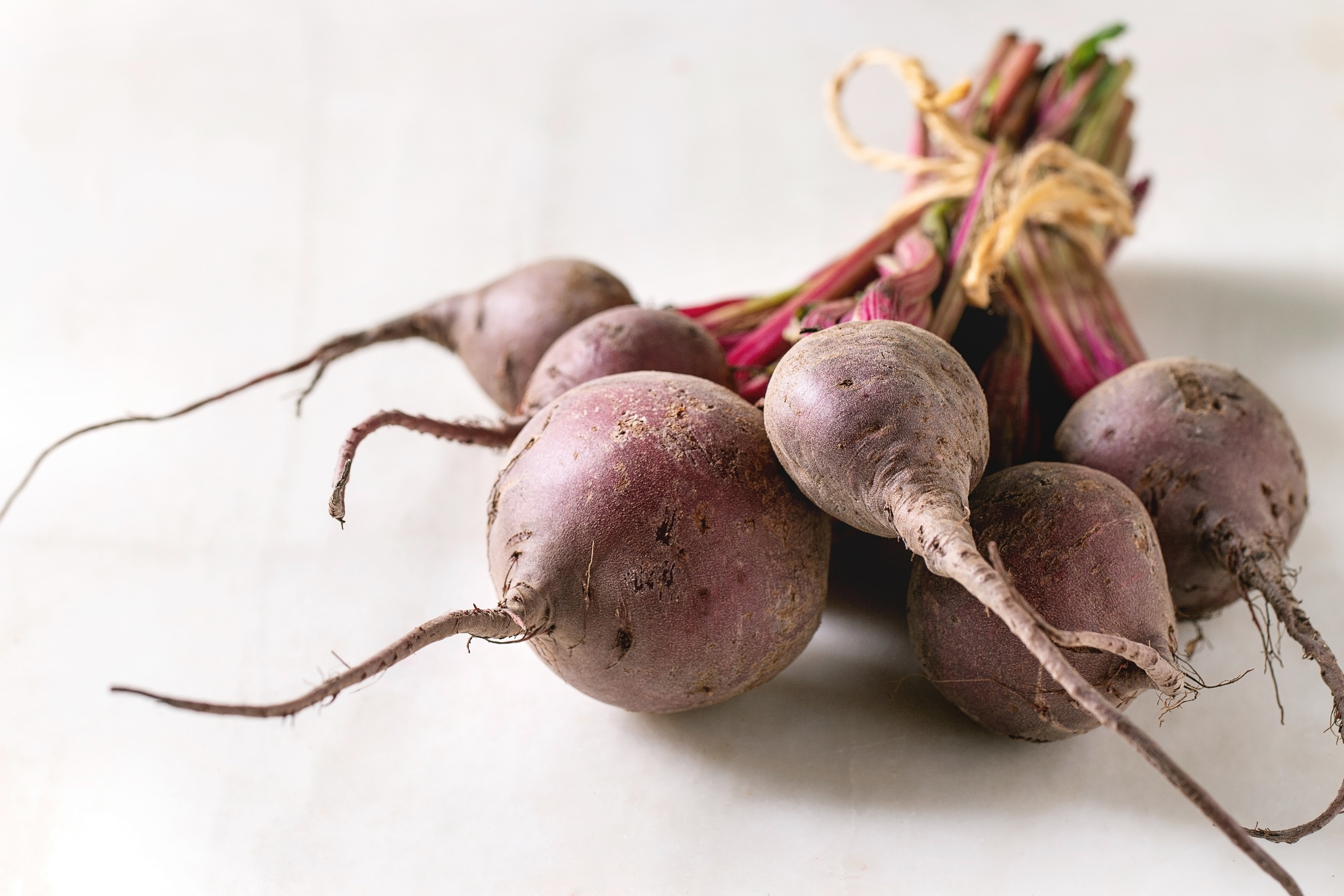 Bundle of young organic garden beetroot over white marble background.