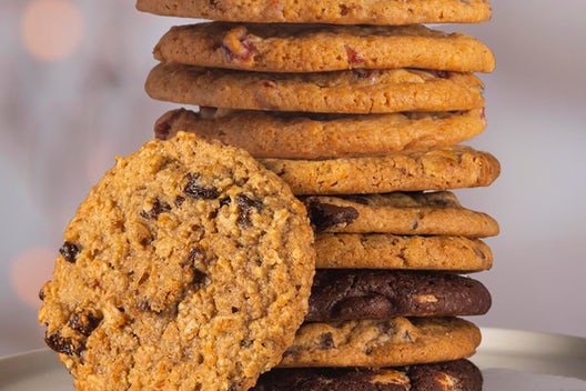 A stack of cookies in a variety of flavors, with one cookie leaning against the tower
