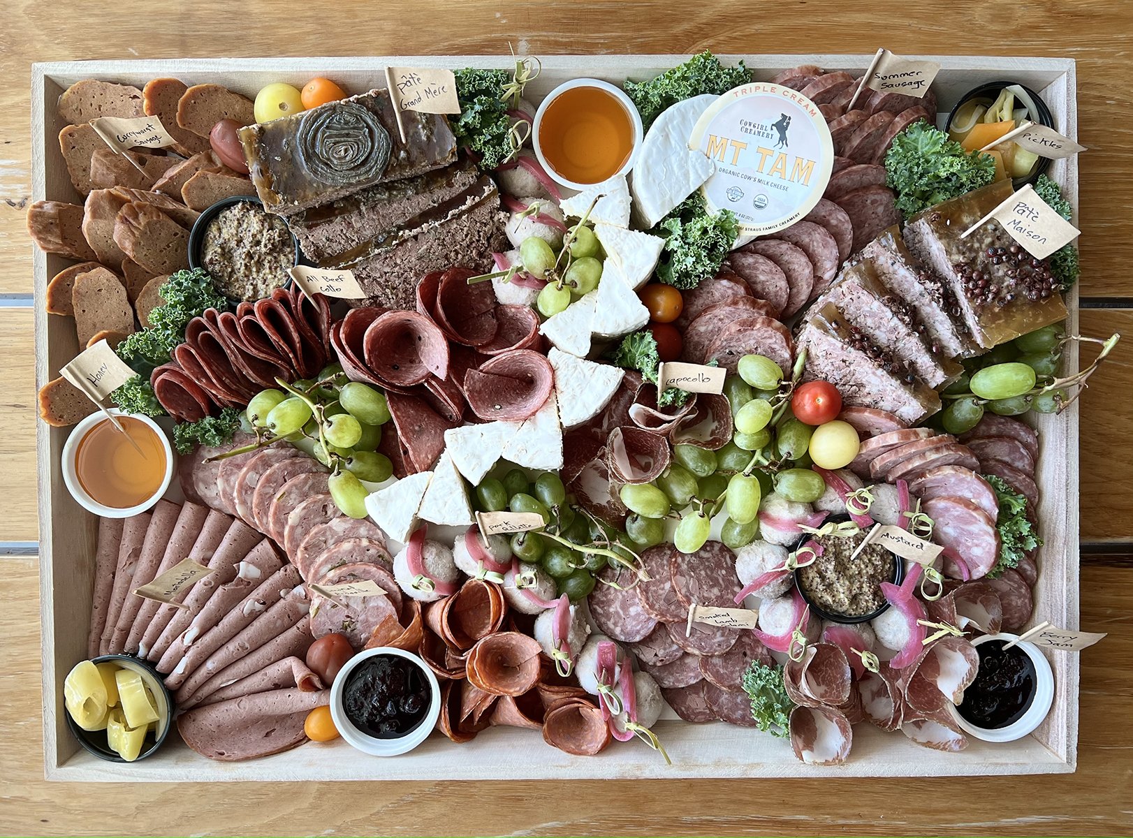 A board of sliced meats, fruits, and cheeses.