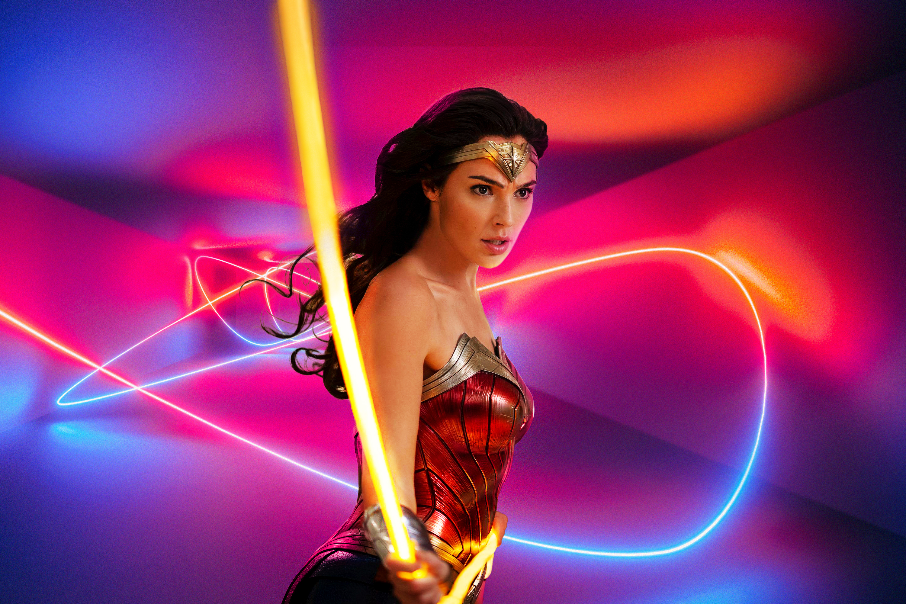 Gal Gadot as Diana flipping her lasso of truth in Wonder Woman 1984, on a blue, red, and purple background