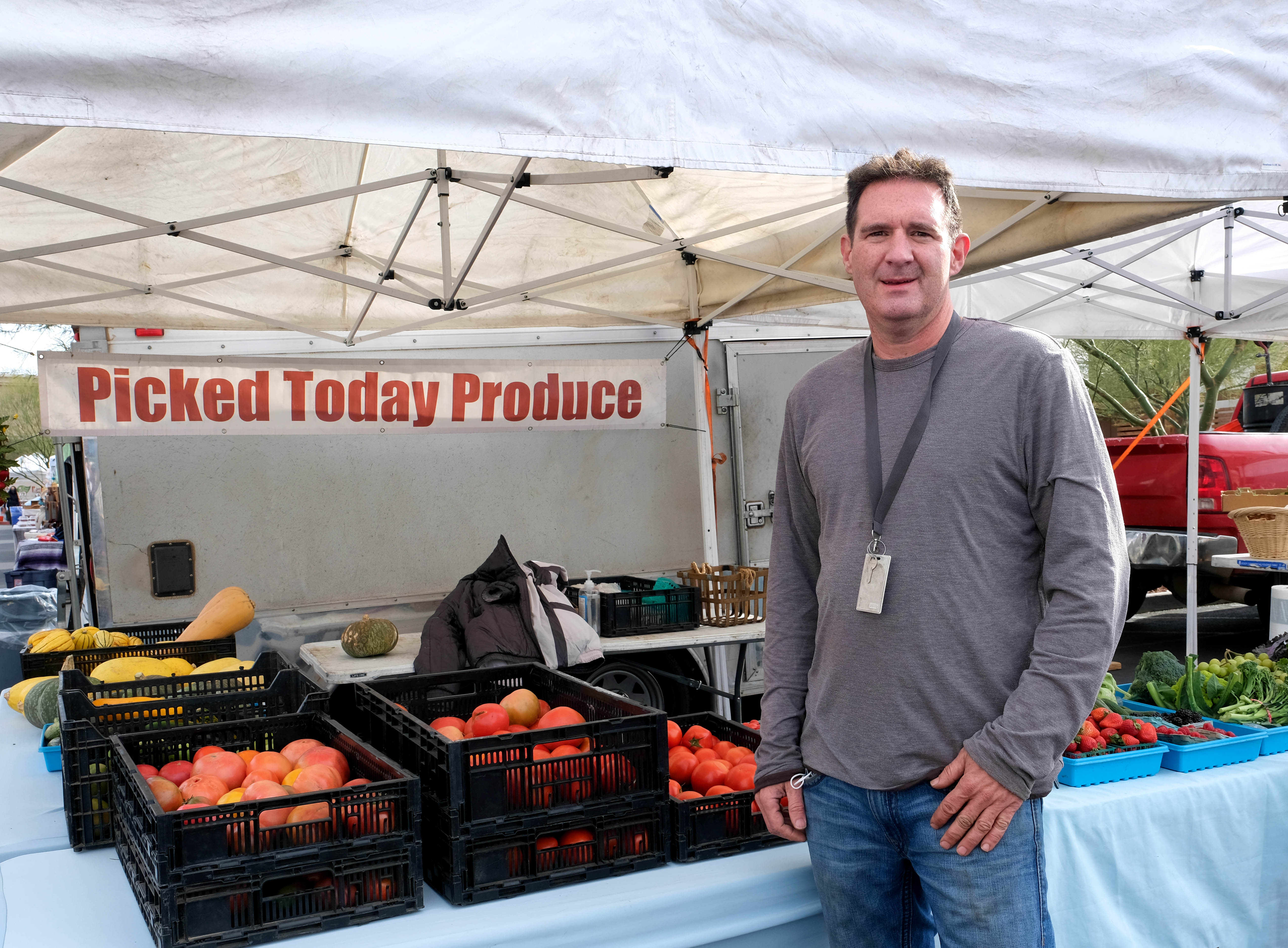 A man stands in front of a produce stand