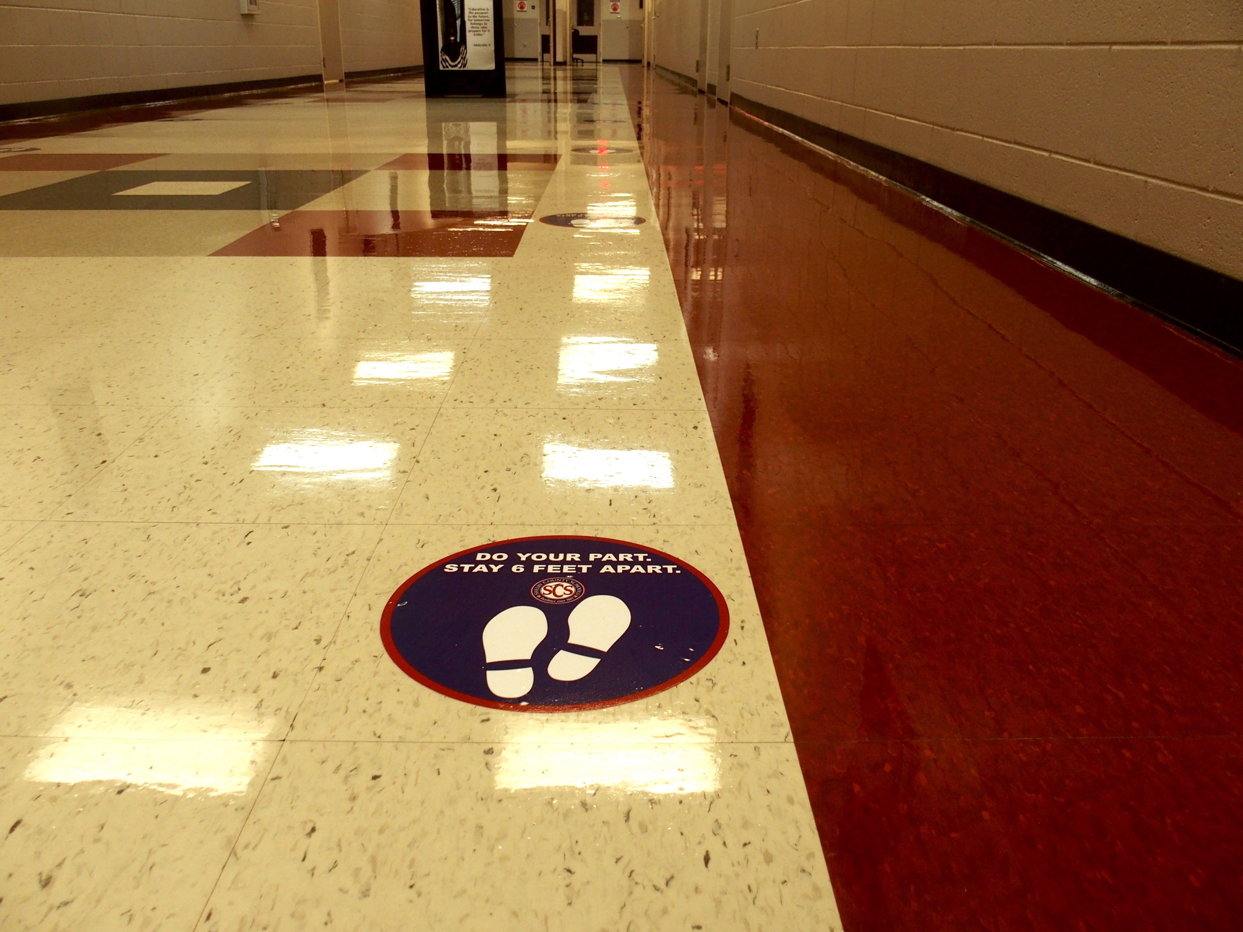 A sticker urging social distancing was placed in a school building hallway