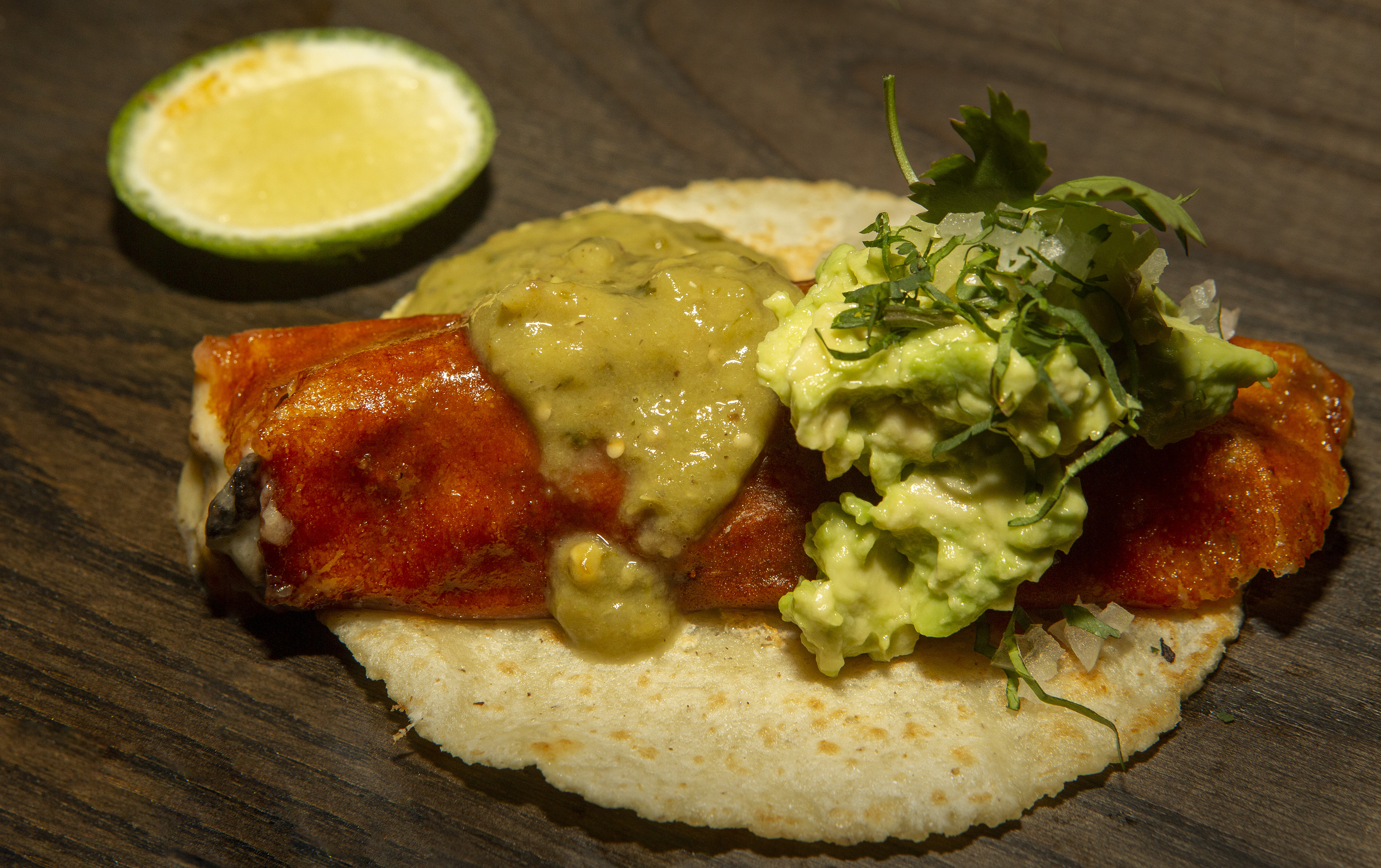 A quesotaco on a tortilla topped with guacamole.