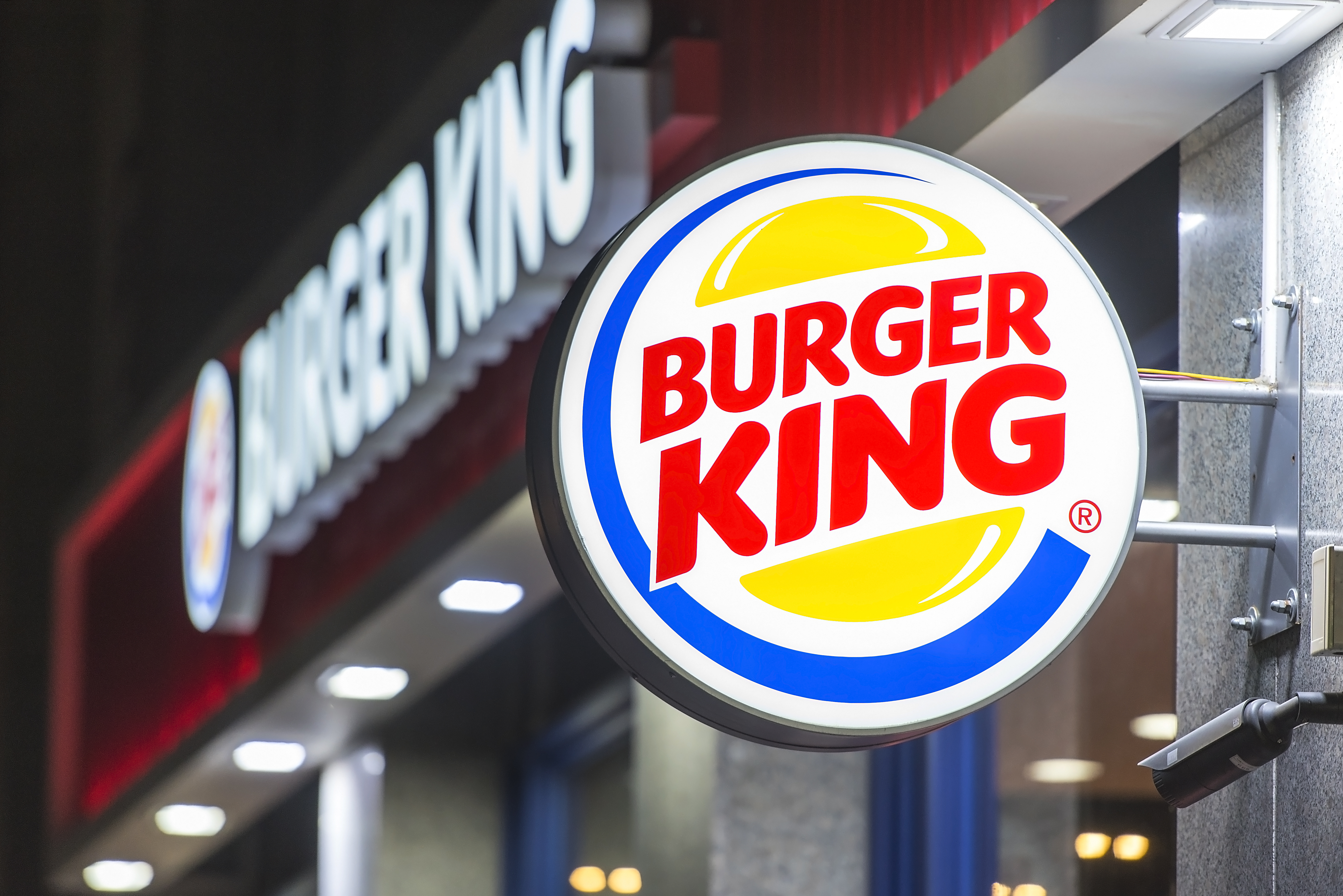 Burger King sign illuminated in foreground, with restaurant in background.