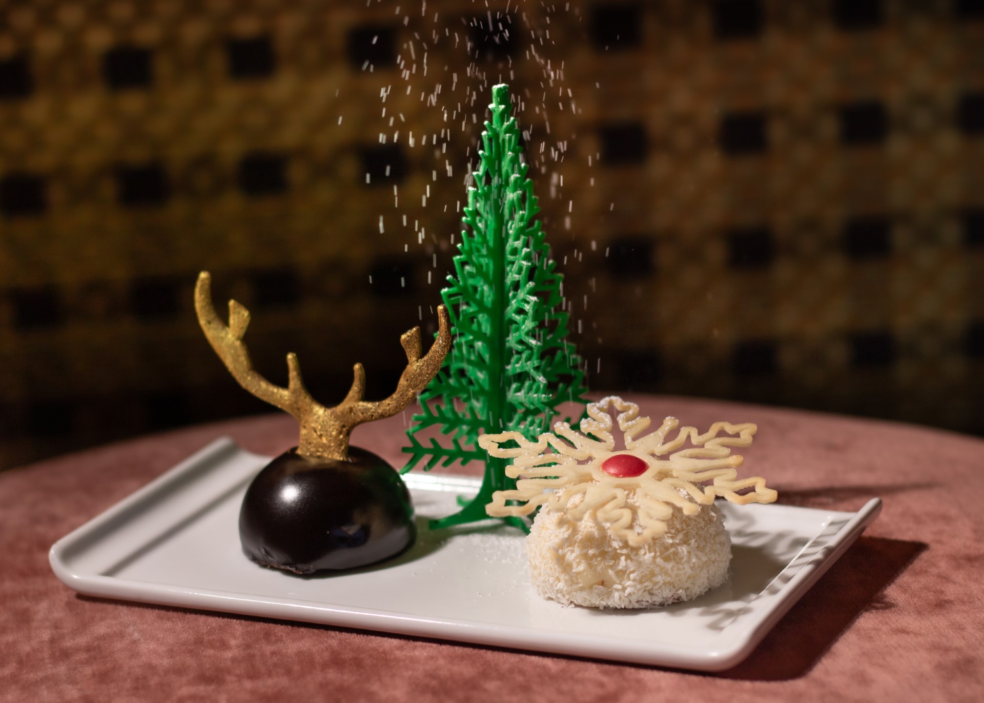 Amrina’s Winter Wonderland dessert features a chocolate cherry mousse cake topped with golden antlers, a red velvet cream cheese mouse, and a Christmas tree prop.