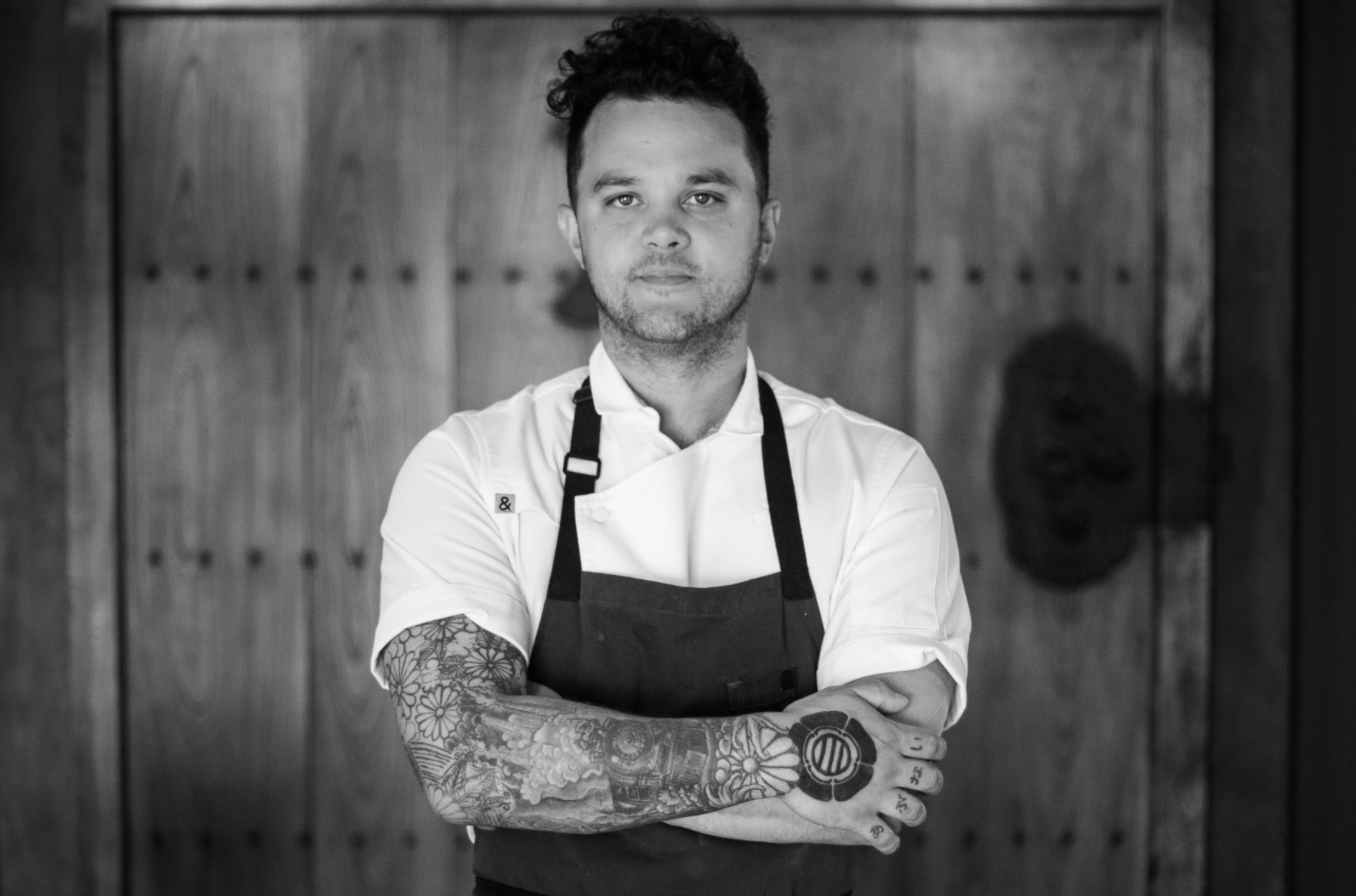 A black and white photo of Canlis chef Brady Williams with his arms folded